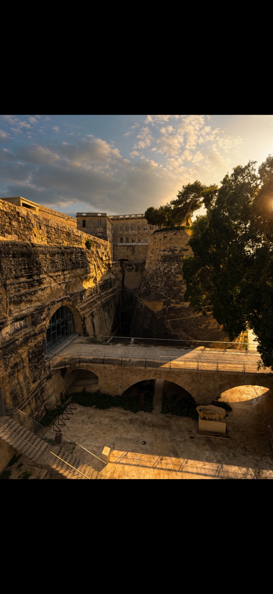 Stone fortress courtyard with arched bridge and defensive walls bathed in golden afternoon sunlight