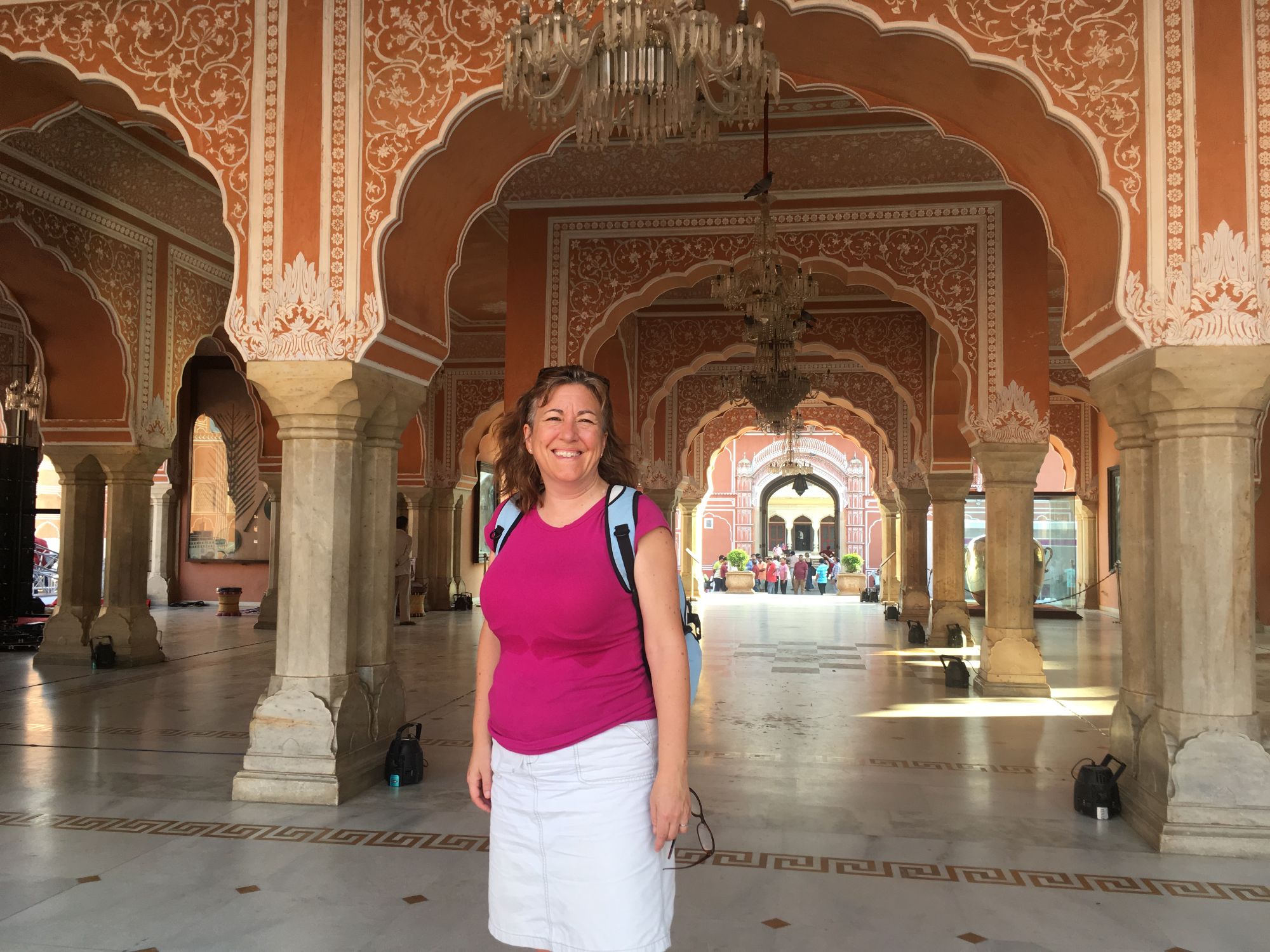 Michelle Whalen walks through a colonnade with red and cream arches and decorative ceiling details in an Indian palace