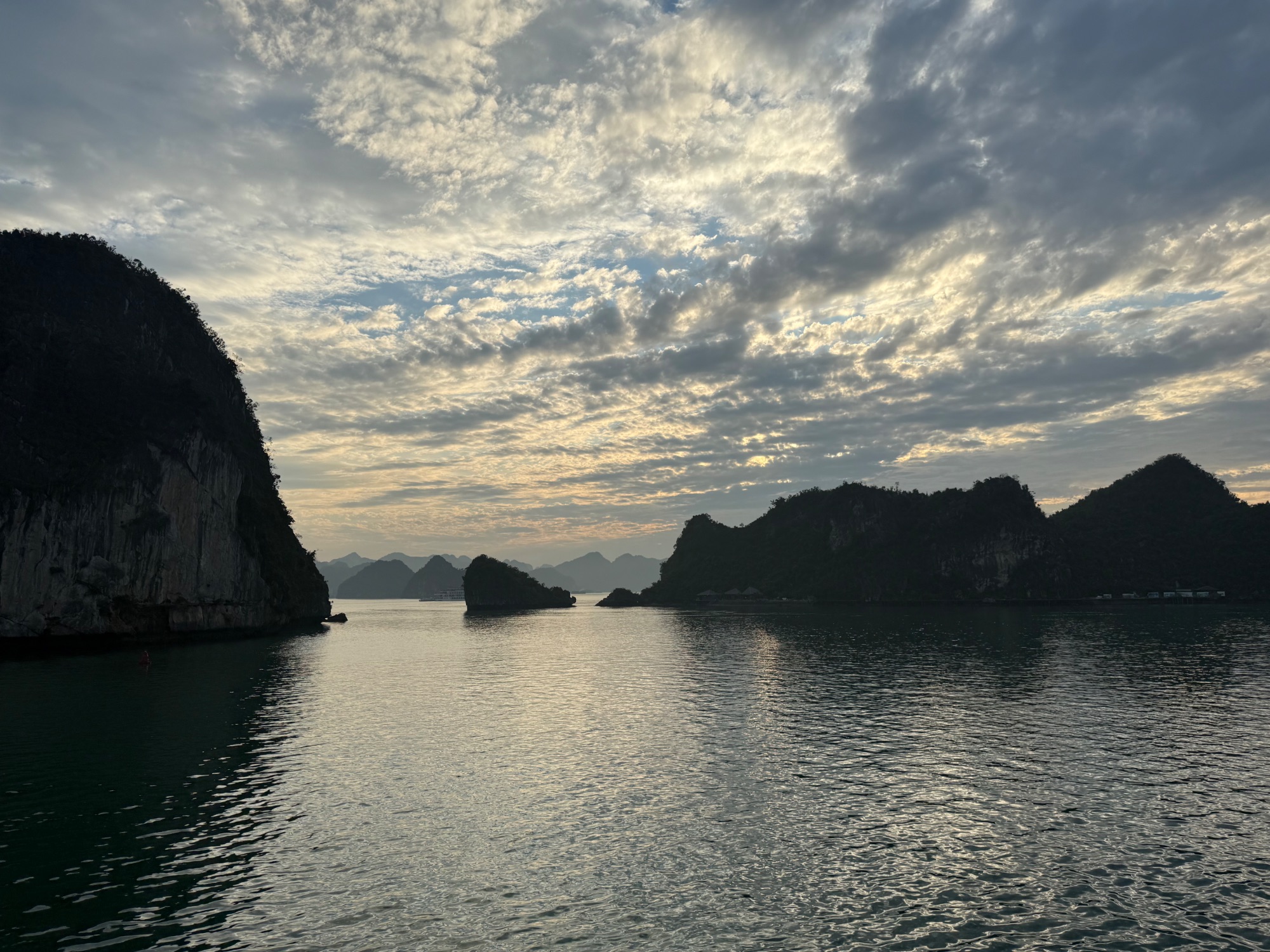 Limestone karst formations rising from calm turquoise waters in Halong Bay, Vietnam at dusk