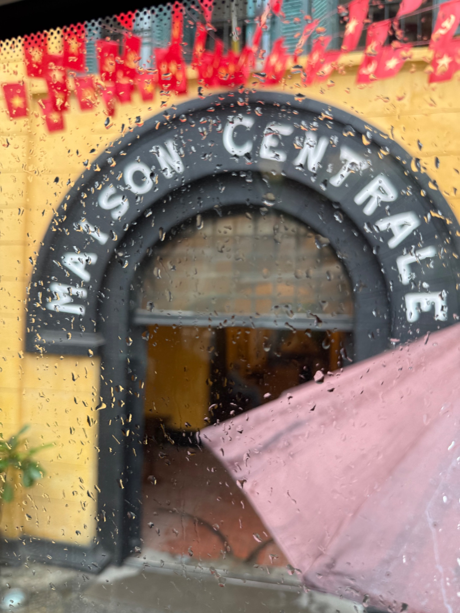 Entrance archway with "SAIGON" text visible, wet from rain with red lanterns in background