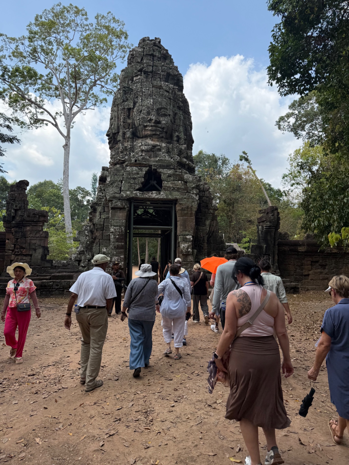 Woman standing in doorway of an ornately carved stone temple entrance at Angkor with decorative architectural details
