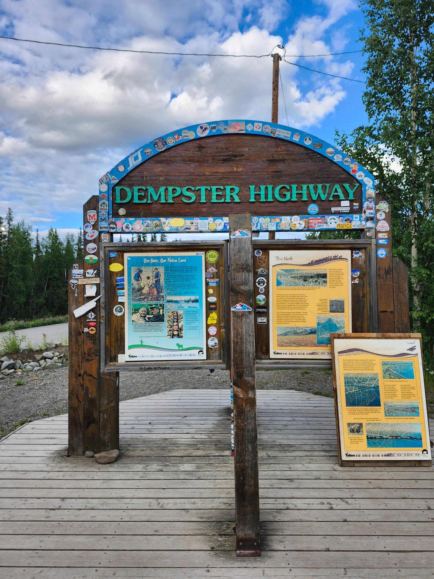 Dempster Highway information kiosk with blue trim and visitor panels on a wooden platform