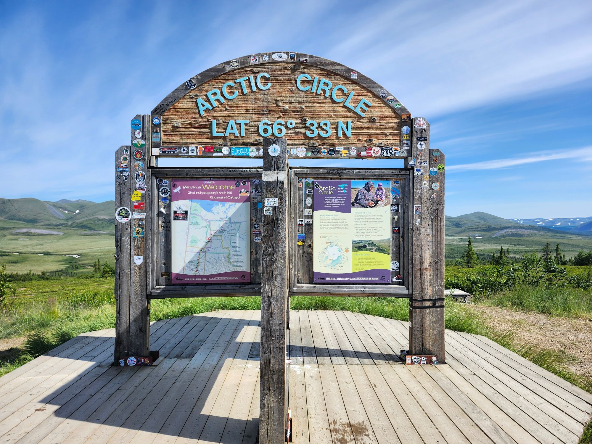 Arctic Circle marker at 66°33'N latitude with information panels and tundra surroundings