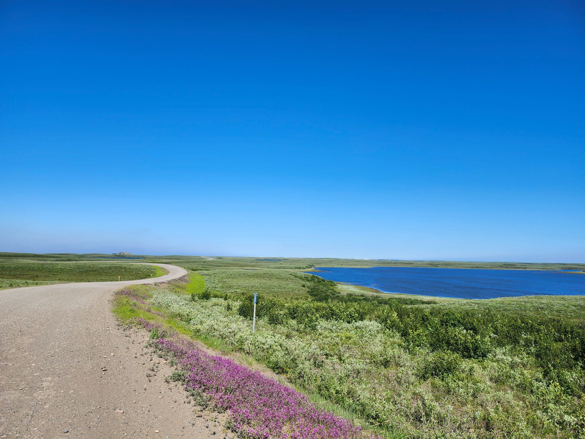 Welcome to Tuktoyaktuk sign featuring pingo illustration with coastal wetlands behind