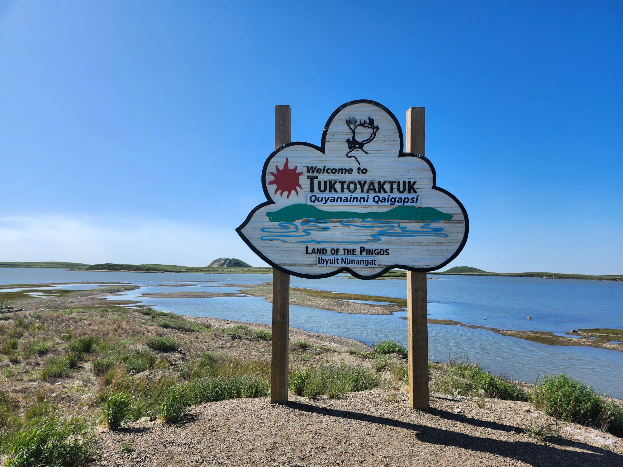 Arctic Ocean road sign in English and Inuinnait with gravel landscape