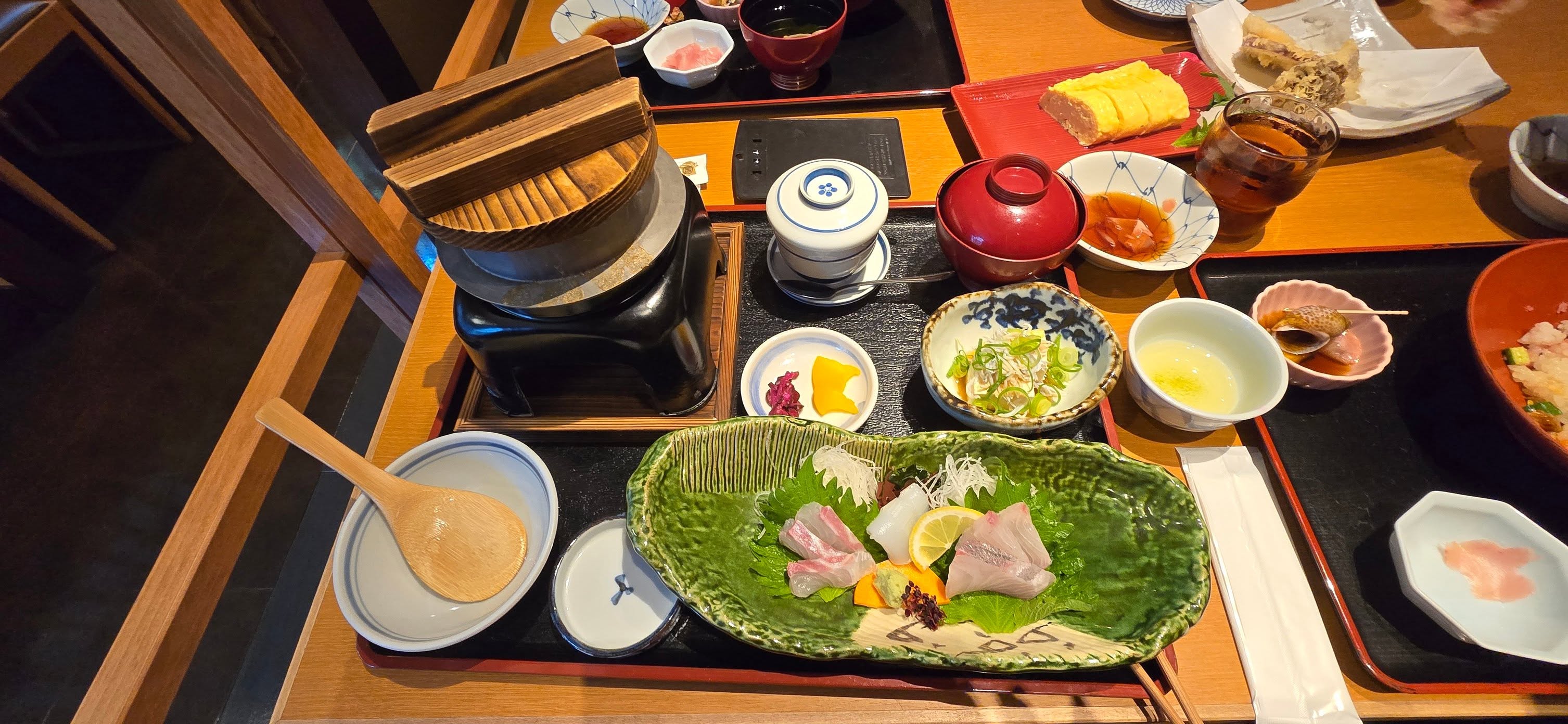 Japanese kaiseki meal with sashimi, soup, and traditional dishes arranged on black lacquered tray