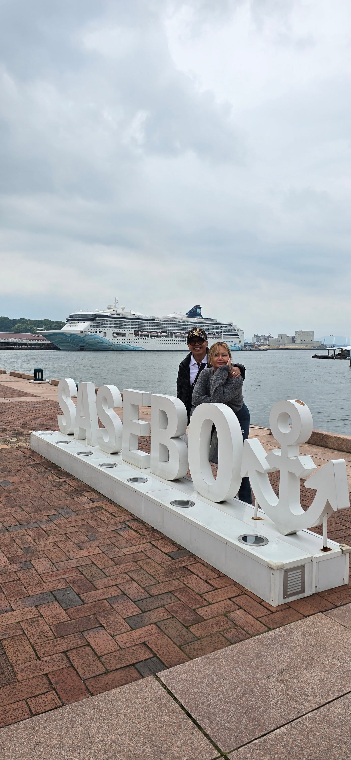 Couple posing with Shibrook cruise ship at port with white letter sign