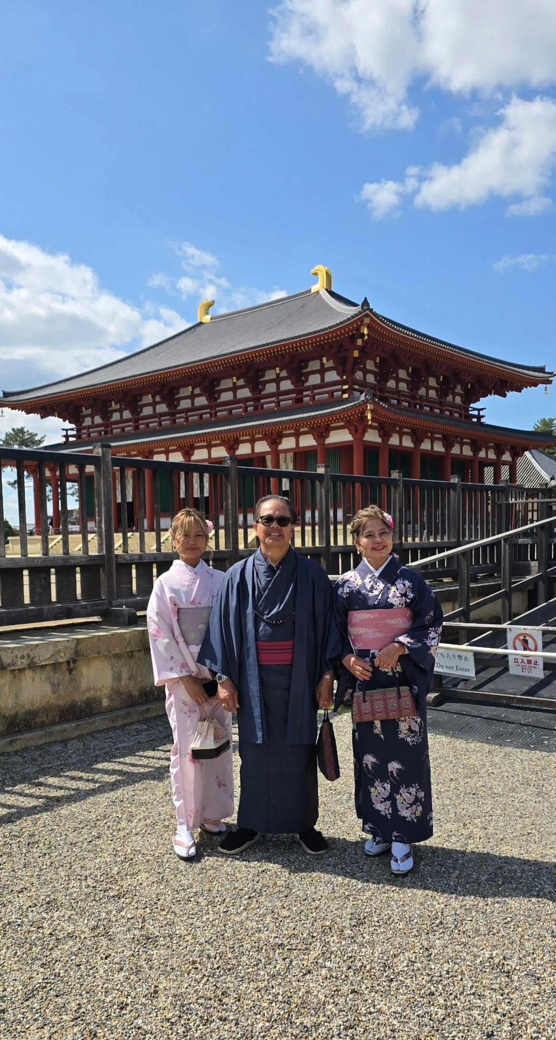 Three people in traditional kimono and yukata at Japanese temple with ornate wooden architecture