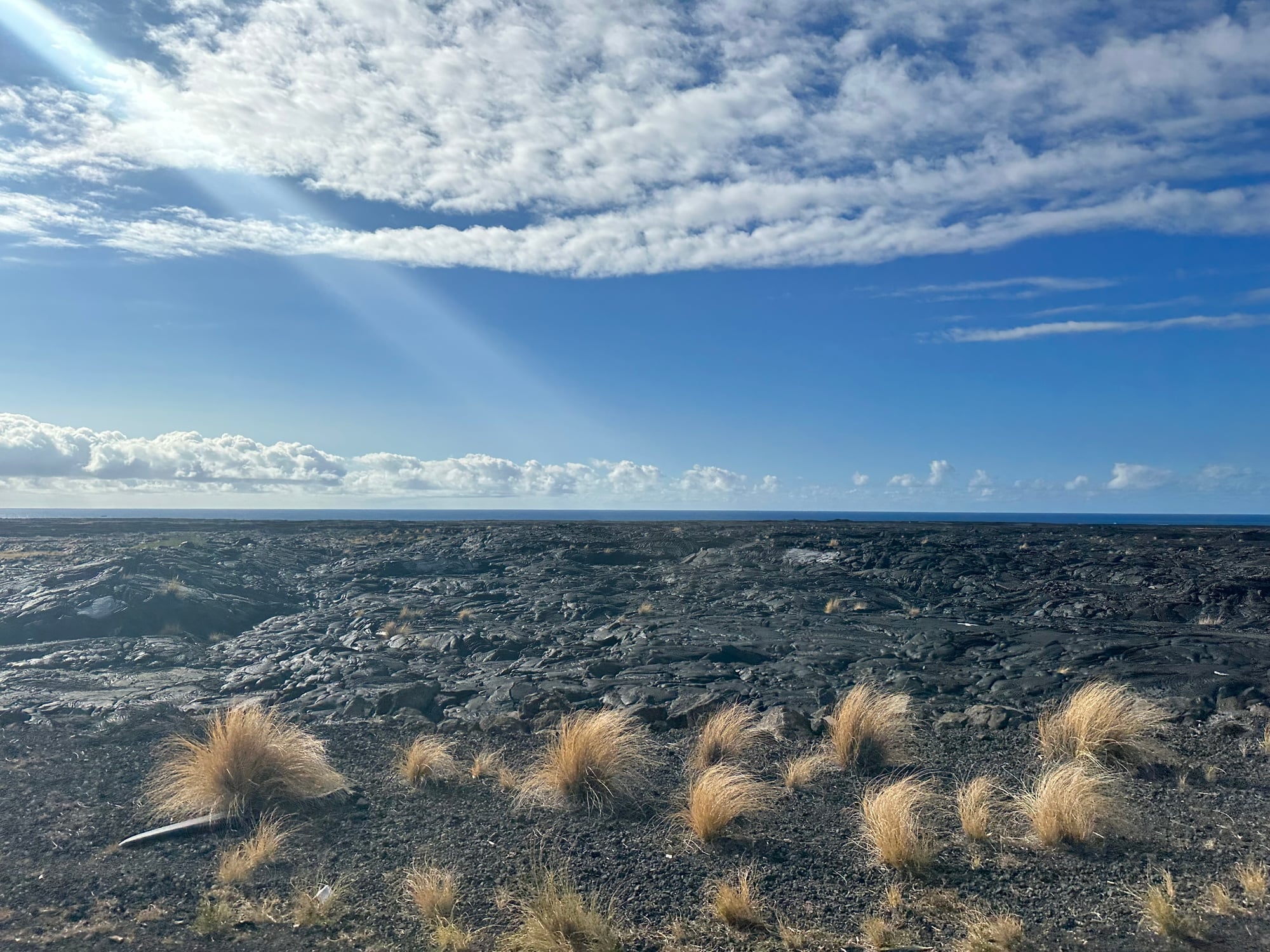 A dramatic mountain landscape with red volcanic ridges, green vegetation, and deep valleys under cloudy skies in Hawaii