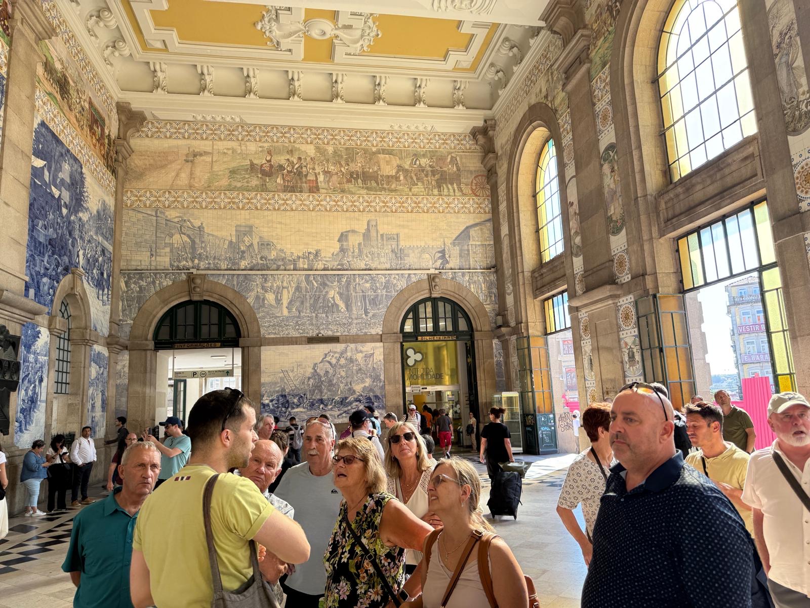 Tour group gathered in an ornate Portuguese train station with blue tile panels and classical architecture