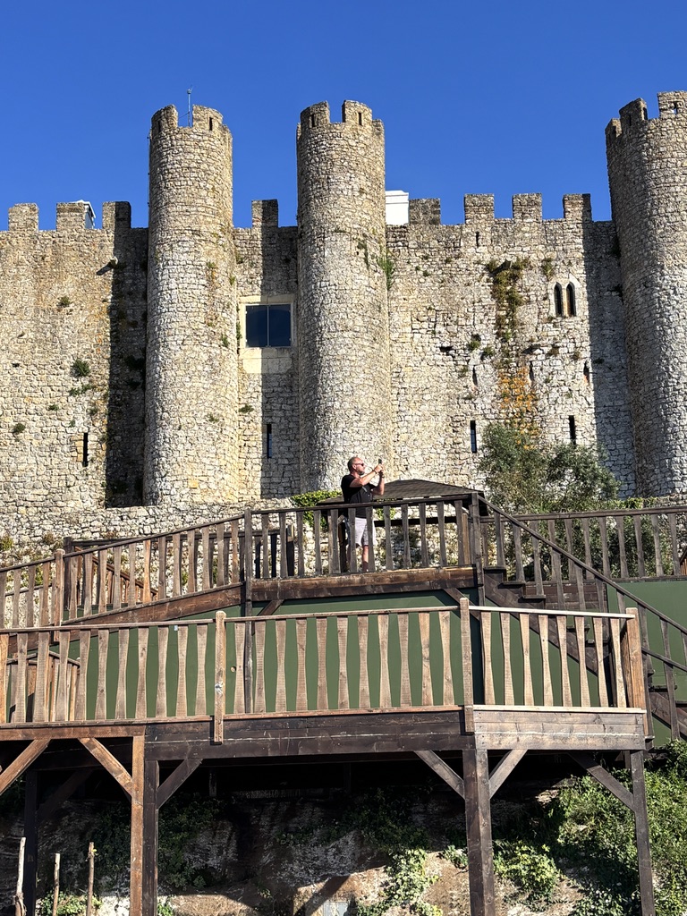 Medieval stone castle with crenellated towers and a wooden viewing platform in foreground