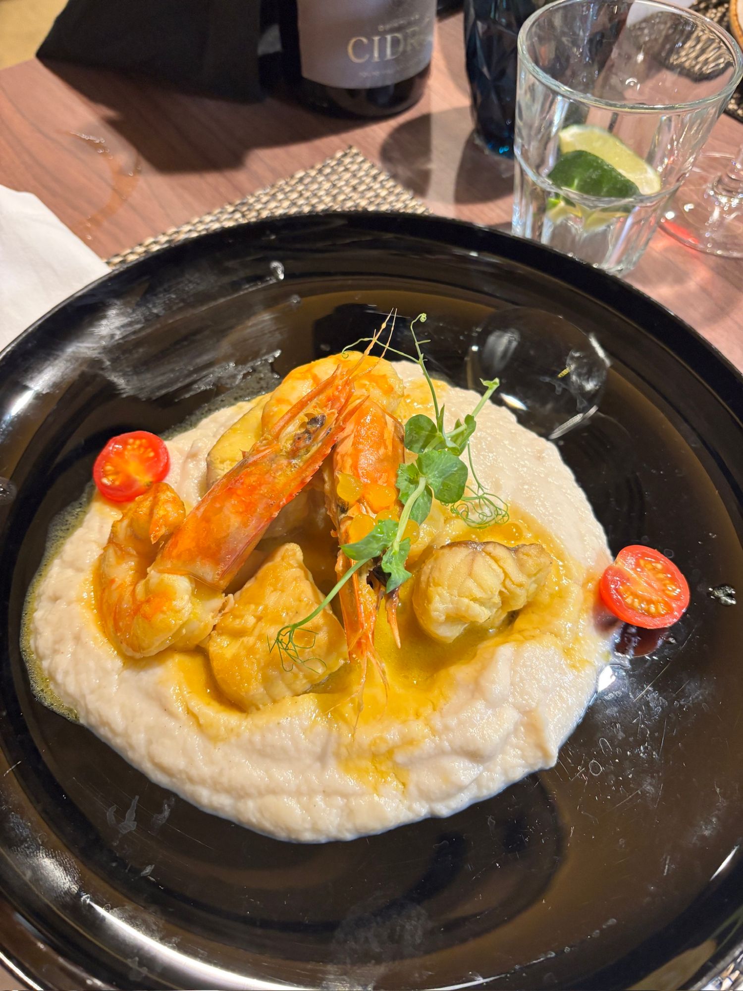 Shrimp and white fish dish with lemon and greens on a white plate at a fine dining restaurant