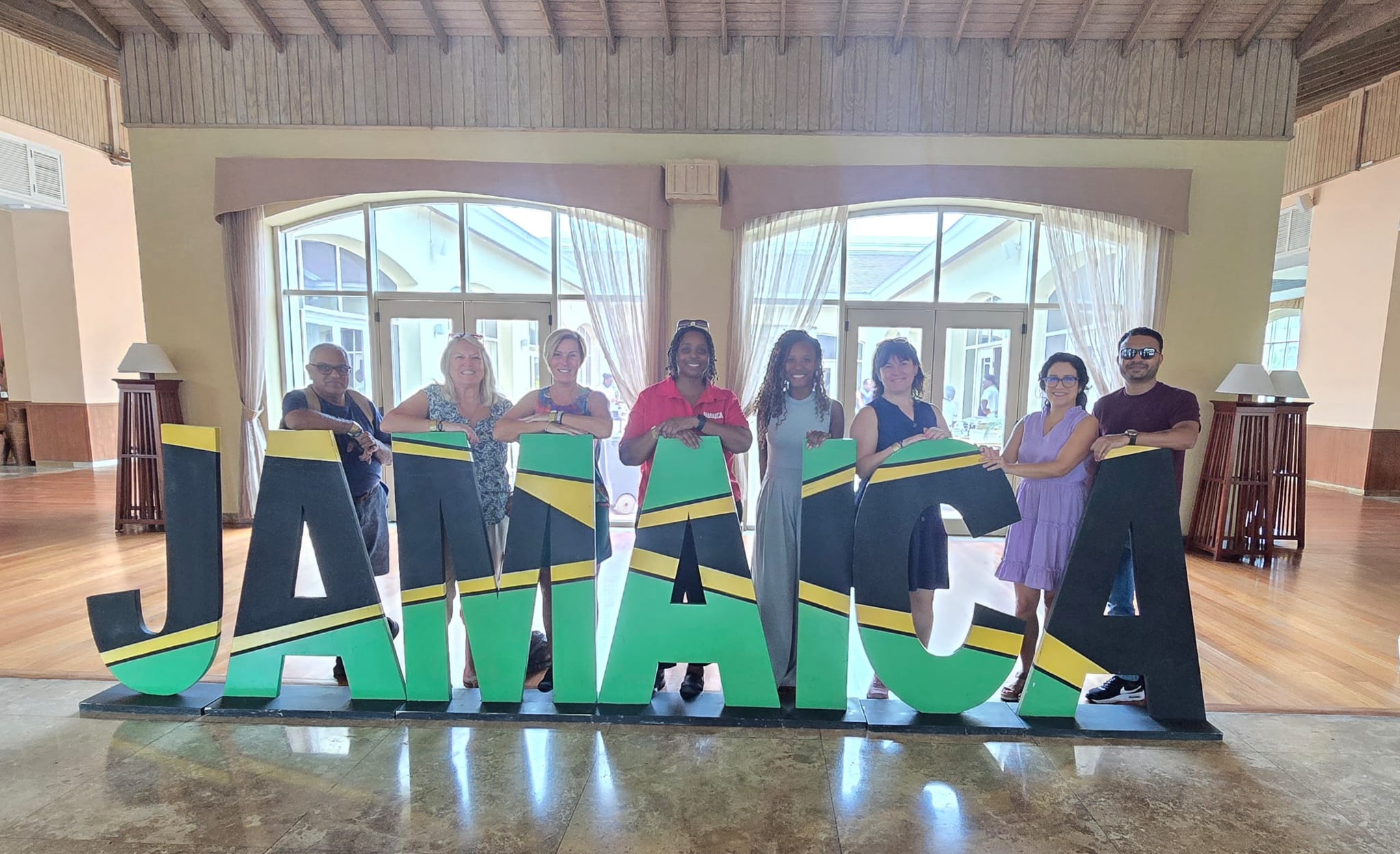 Group of nine people posing with a large Jamaica flag sign at the resort