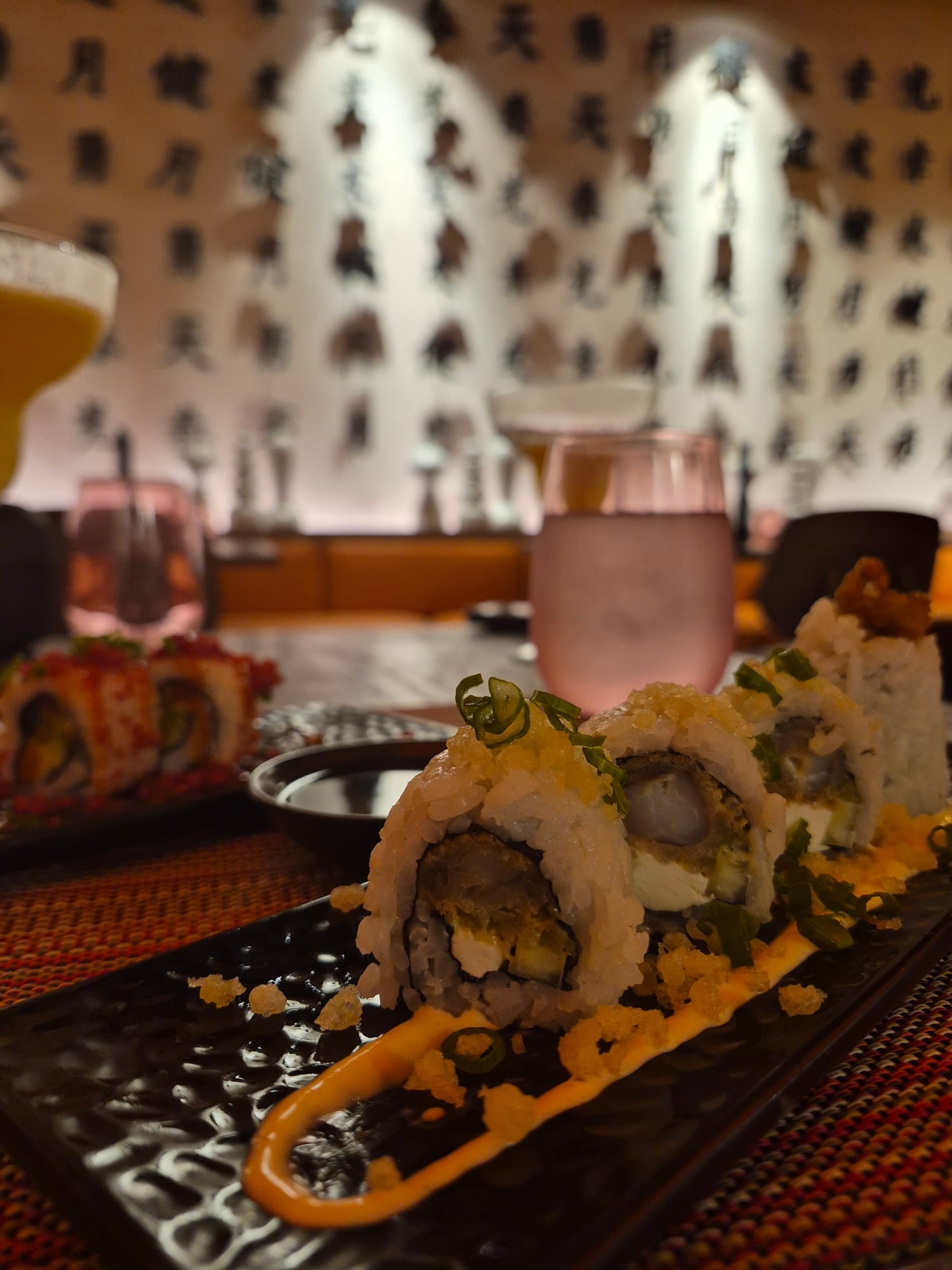 Close-up of sushi rolls and cocktails with decorative white feather backdrop