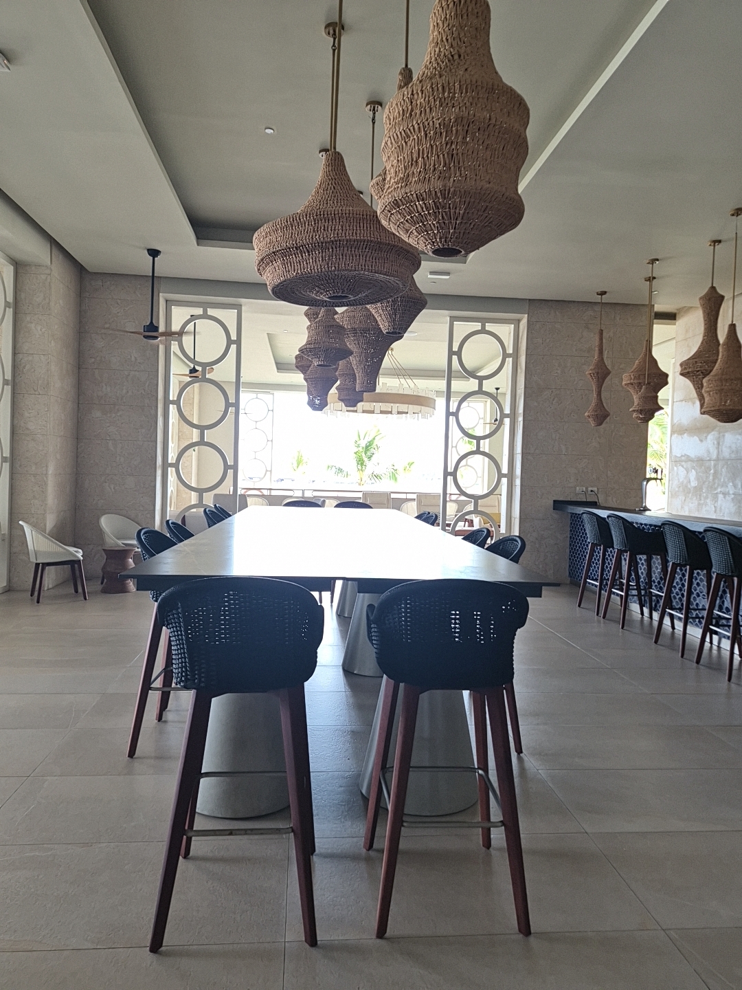 Modern dining space with white oval table, navy chairs, and woven pendant lights