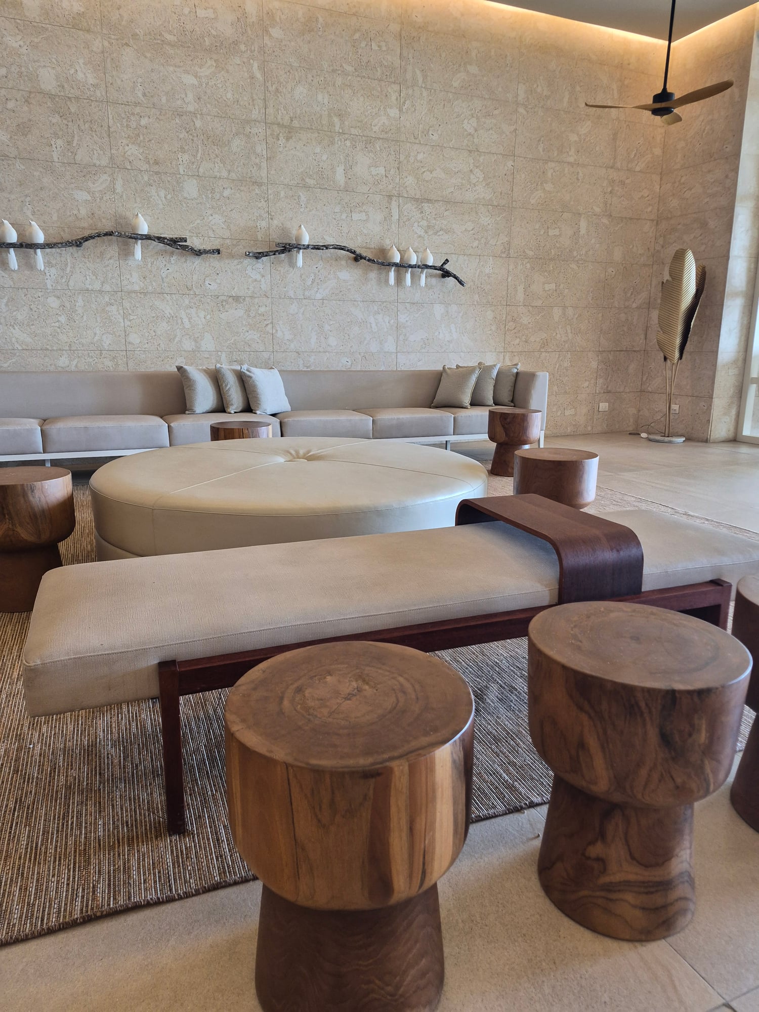 Minimalist lounge with cream curved sofa, wooden side tables, and decorative wall branches