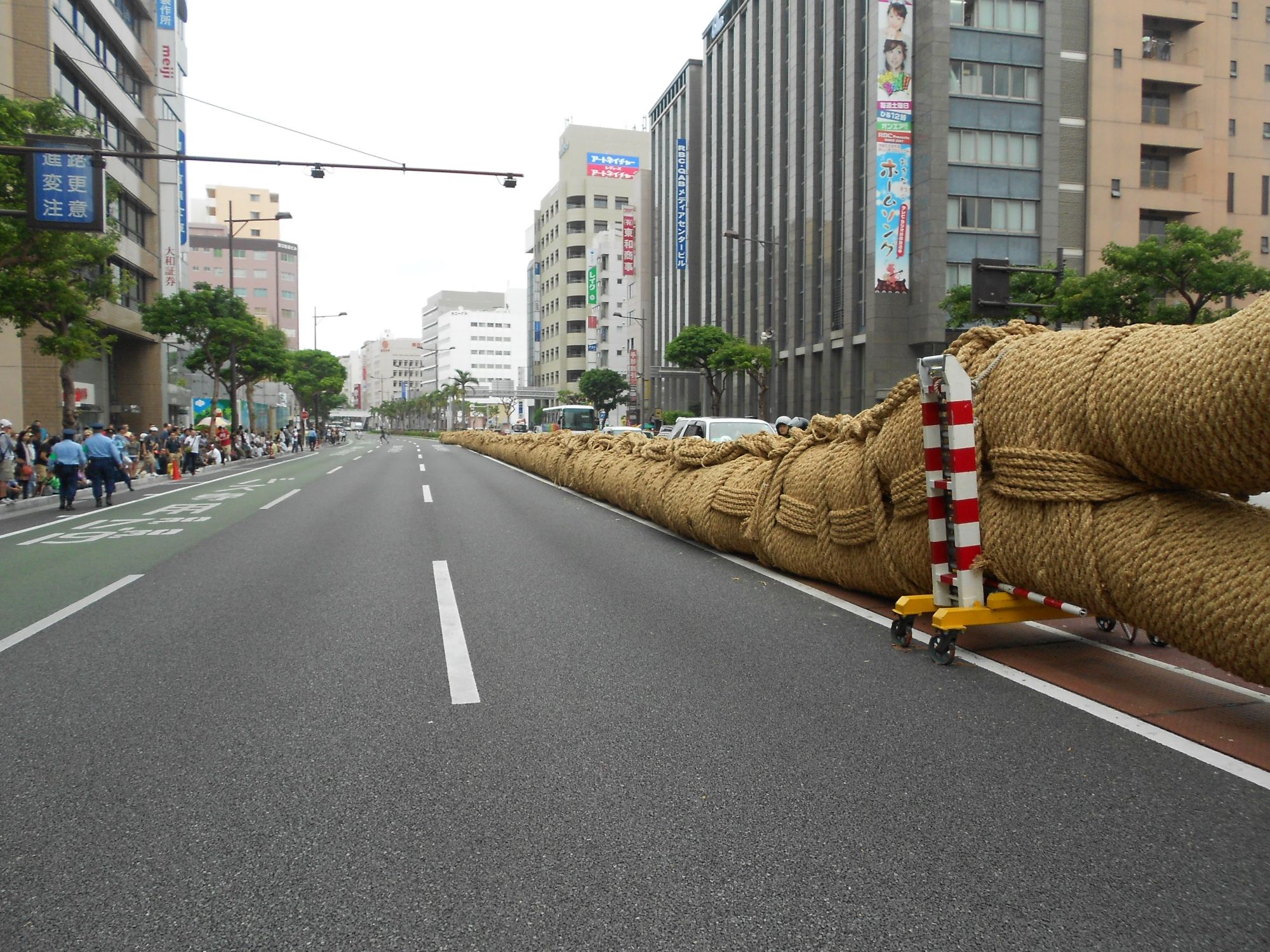 Enormous coiled rope displayed on an urban street with buildings and spectators in the background