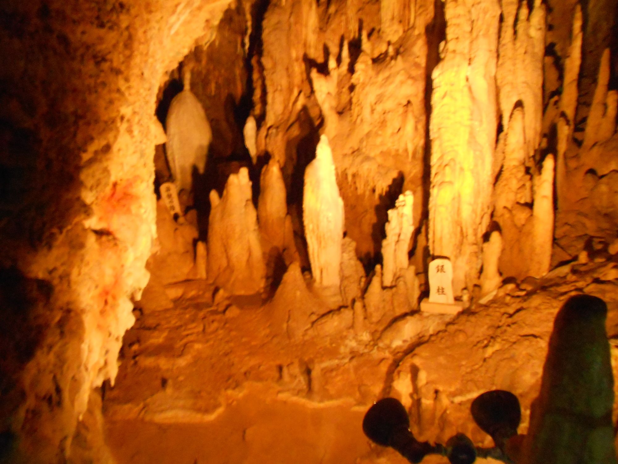 Illuminated cave interior with stalactites and stalagmites glowing in warm orange tones