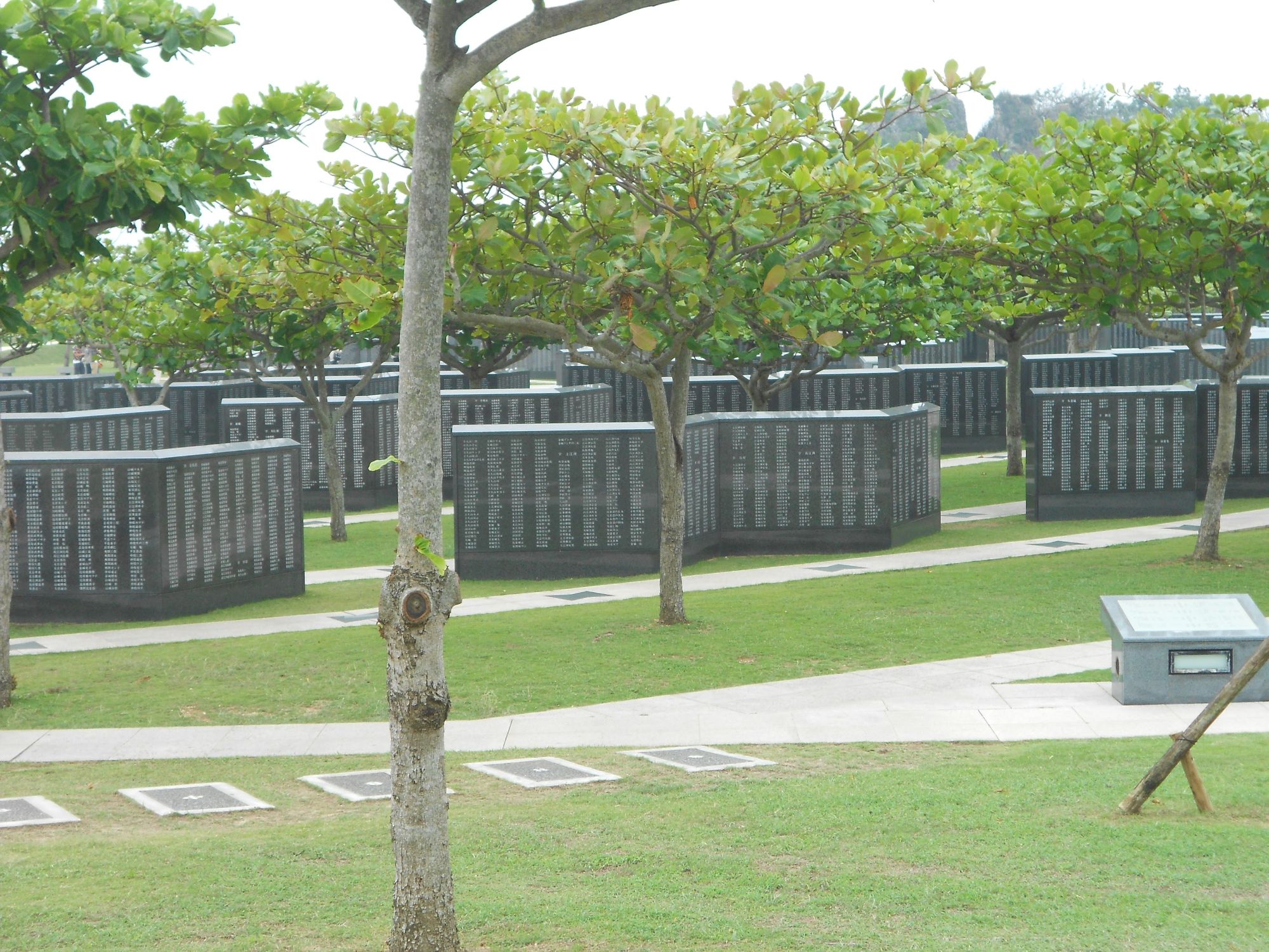 Memorial park with curved black walls inscribed with names, green grass and trees in Okinawa