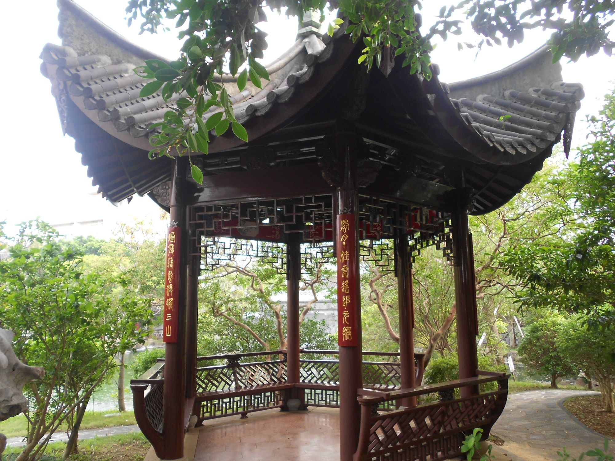 Traditional dark wooden pavilion with curved roof and ornate railings overlooking water