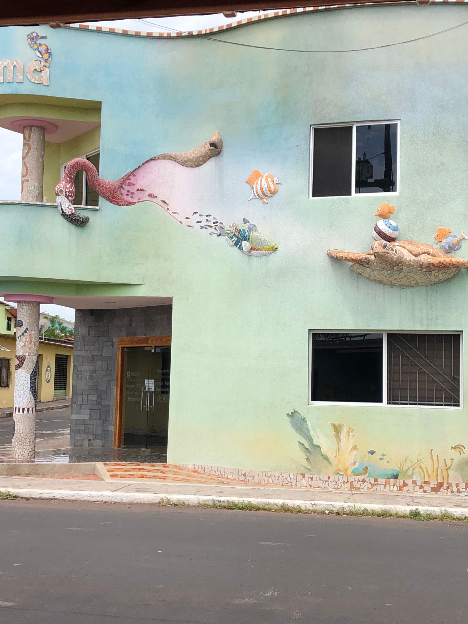 Colorful street mural on a pale green building depicting a sea snake and tropical fish