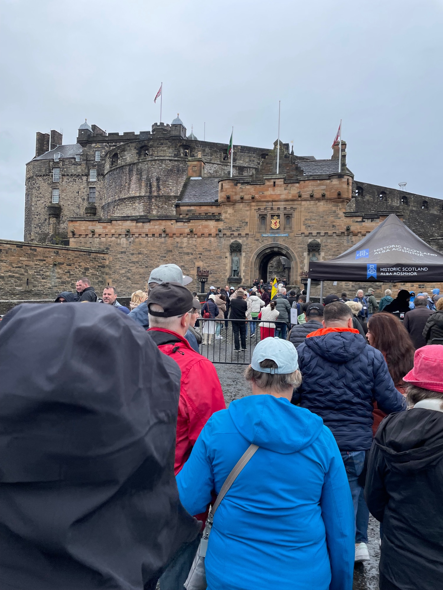 Crowds gather at Edinburgh Castle entrance with Historic Scotland signage visible on a cloudy day