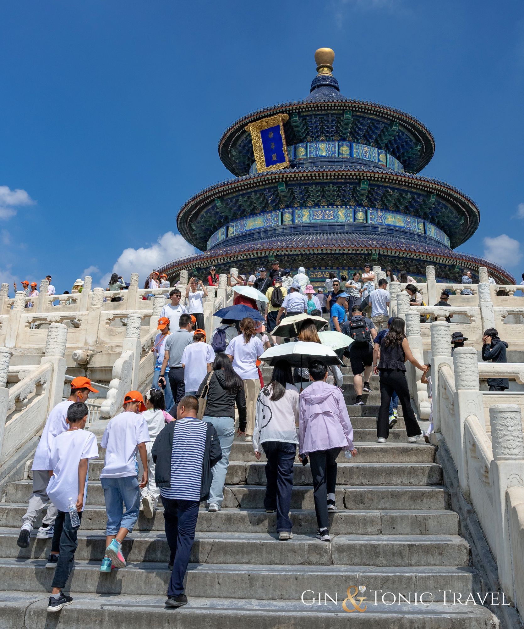 Tourists climbing white marble stairs toward the Temple of Heaven's circular Hall of Prayer for Good Harvests in Beijing