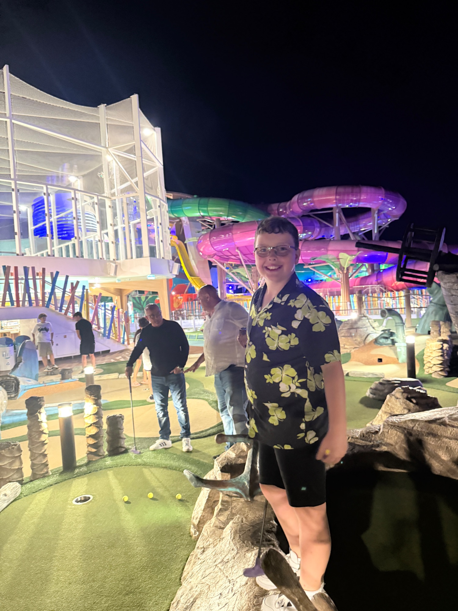 Person rock climbing on an illuminated climbing wall at night aboard a cruise ship