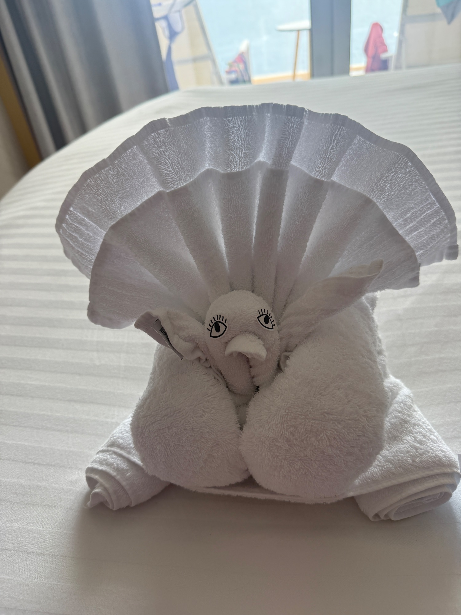 Towel folded into a decorative shell shape with embroidered face on a ship cabin bed