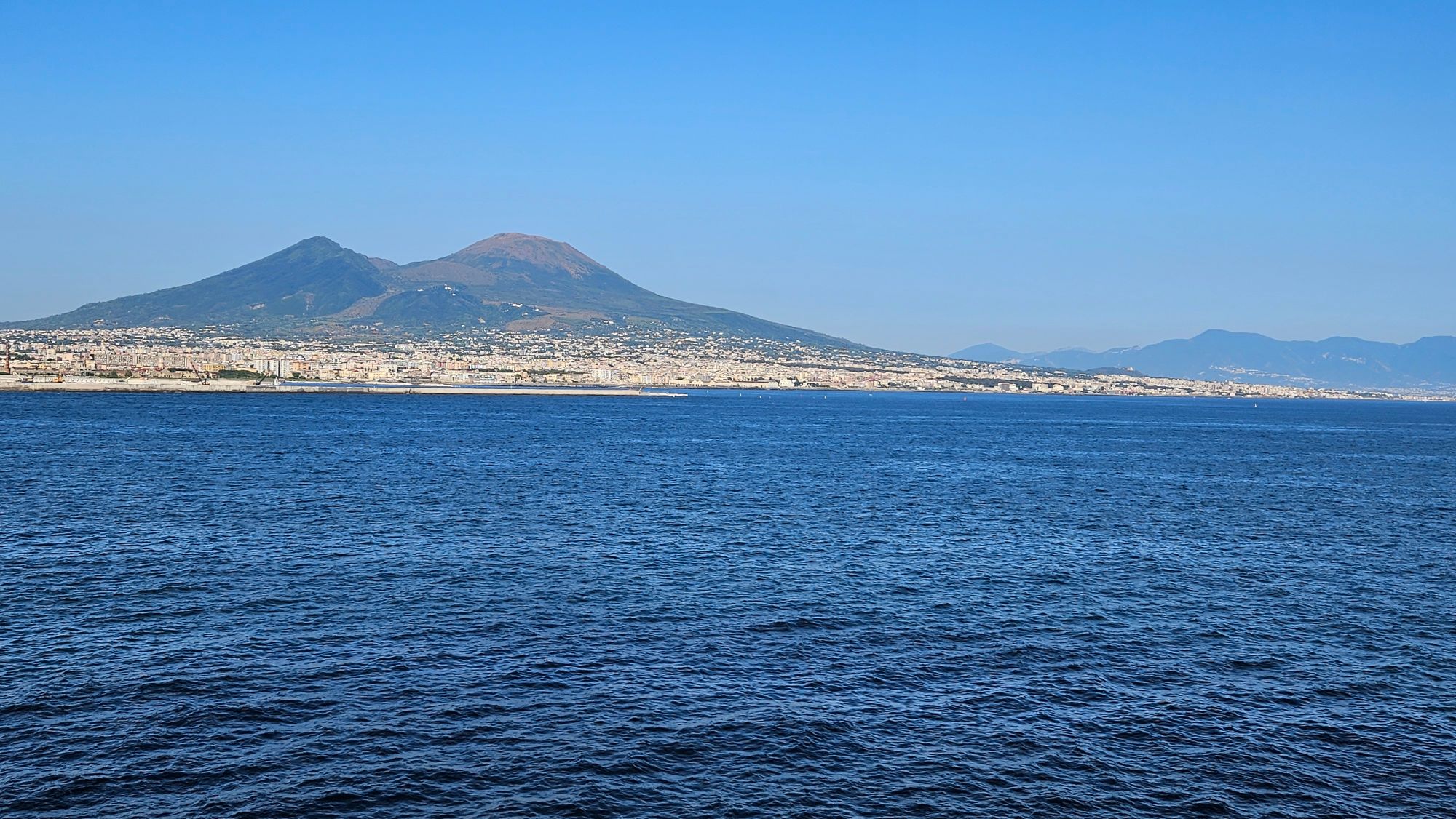Ruins of Pompeii with standing columns and arched structures, Vesuvius visible in the background