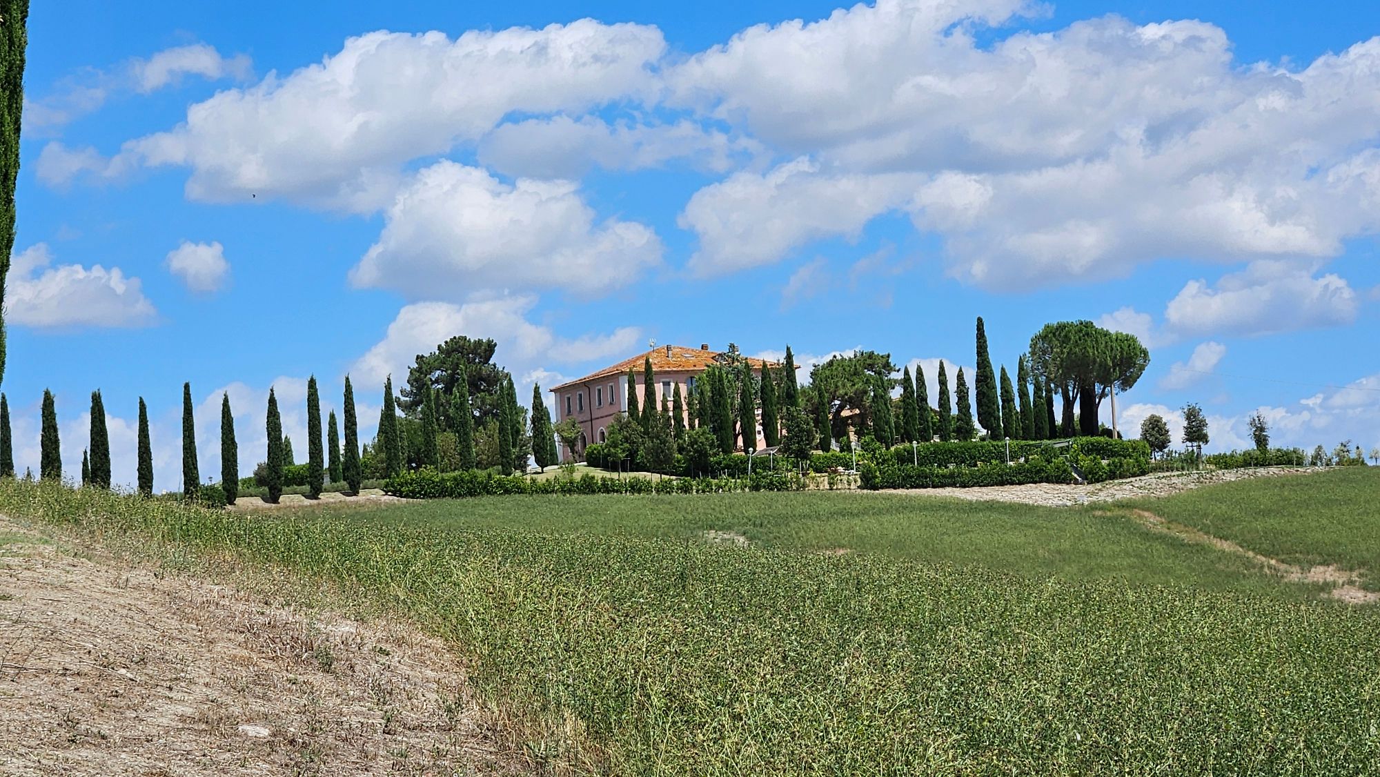 Villa surrounded by cypress trees in the Tuscan countryside with mountains in the distance