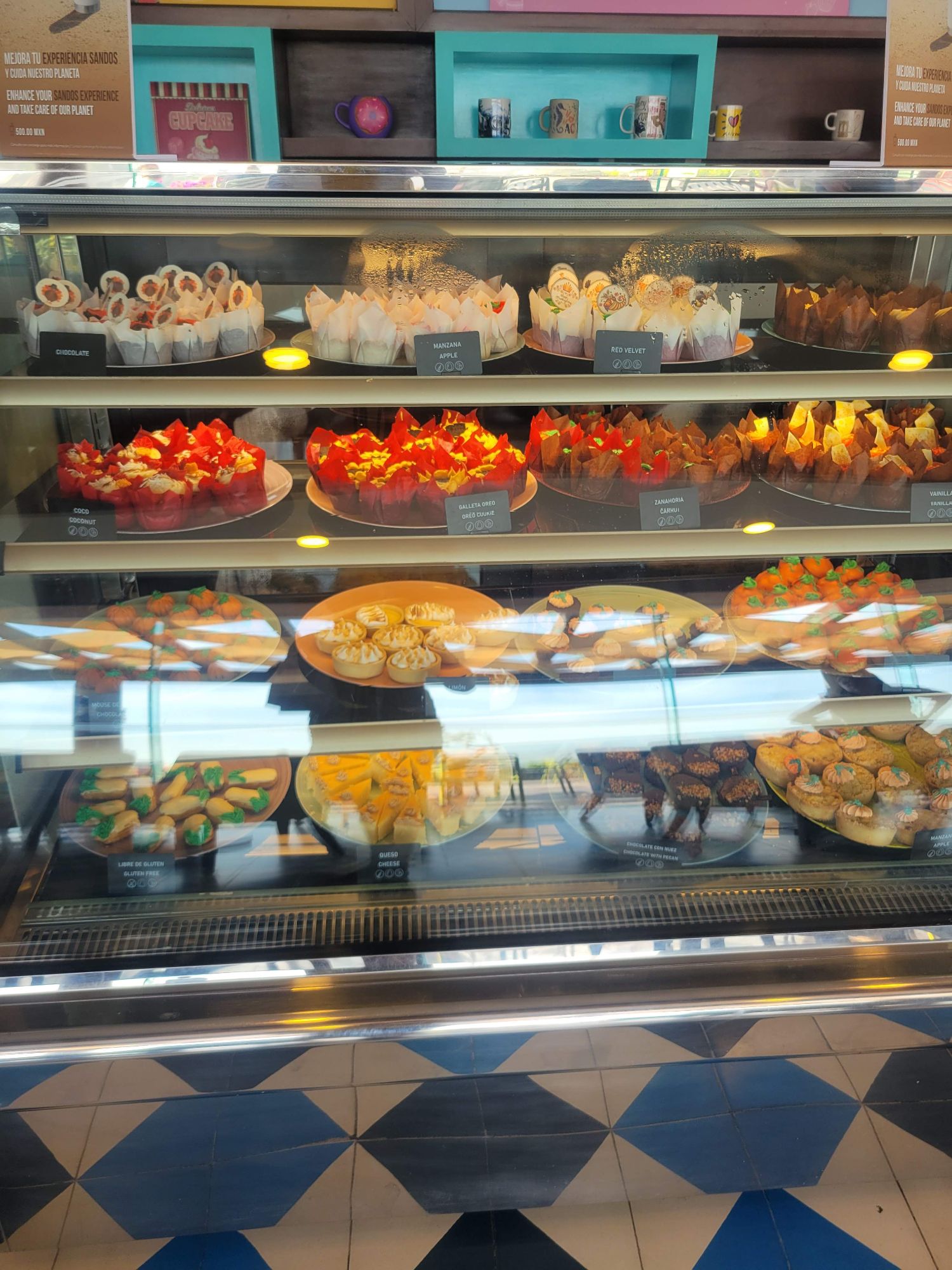Bakery display case filled with colorful decorated cupcakes and pastries with red, orange, and yellow frosting