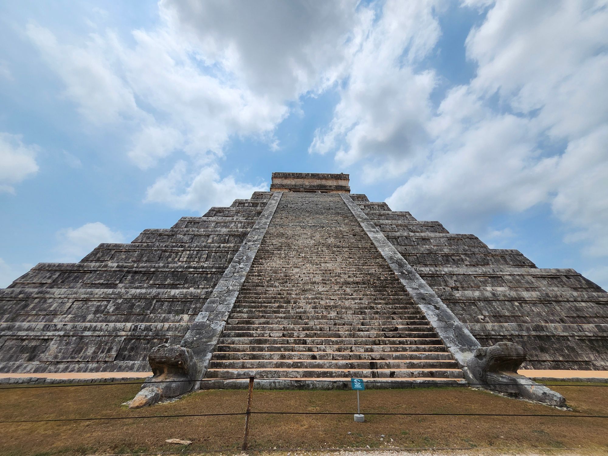 Frontal view of El Castillo pyramid showing symmetrical stepped sides and central staircase