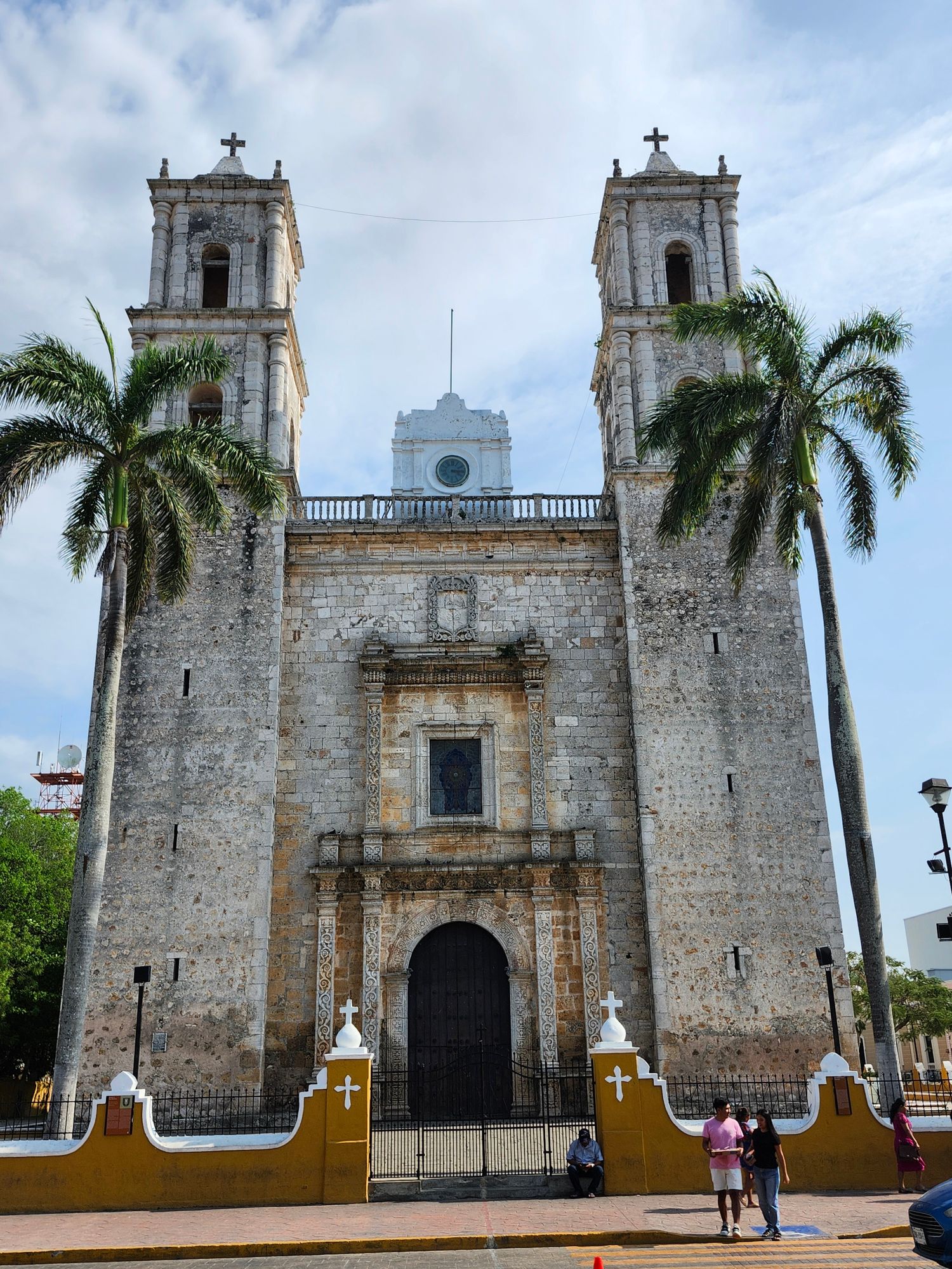 Colonial church with twin bell towers and ornate stone facade, palm trees flanking entrance