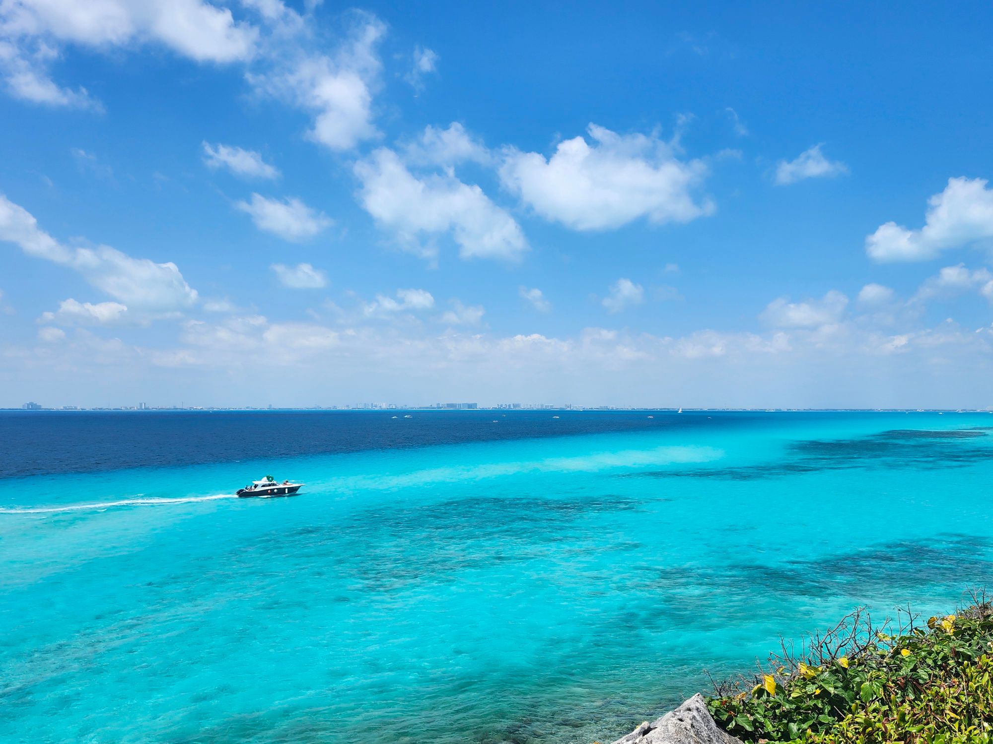 Turquoise Caribbean waters with boat and coral reef visible from elevated coastal viewpoint