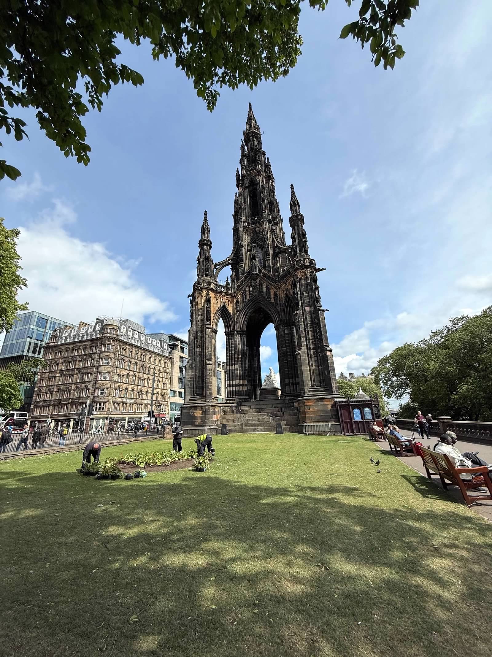 Gothic monument in park setting with historic stone buildings and green space in Edinburgh