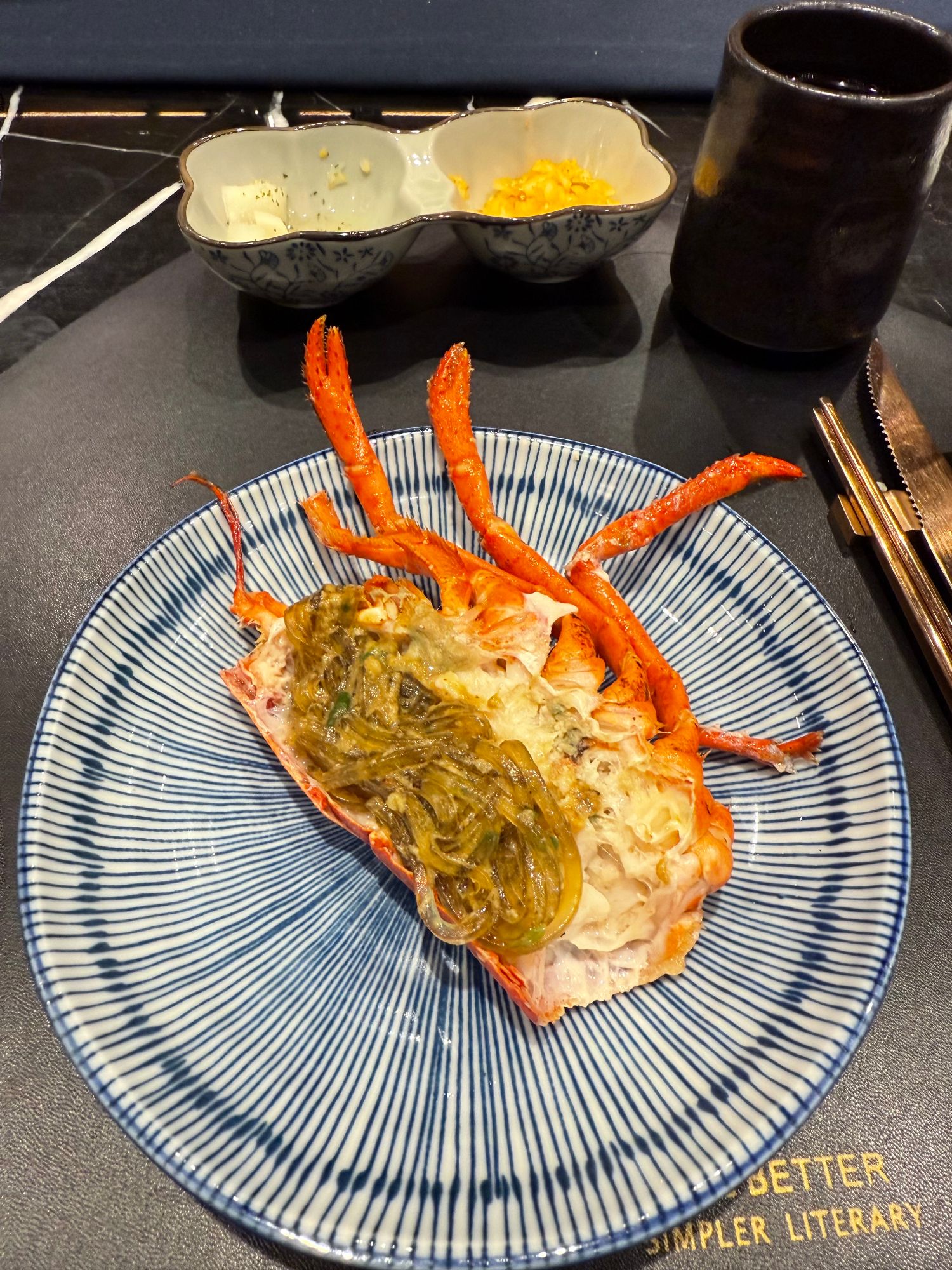 A man holds a cooked crab with prominent orange legs on a blue and white patterned plate at a restaurant