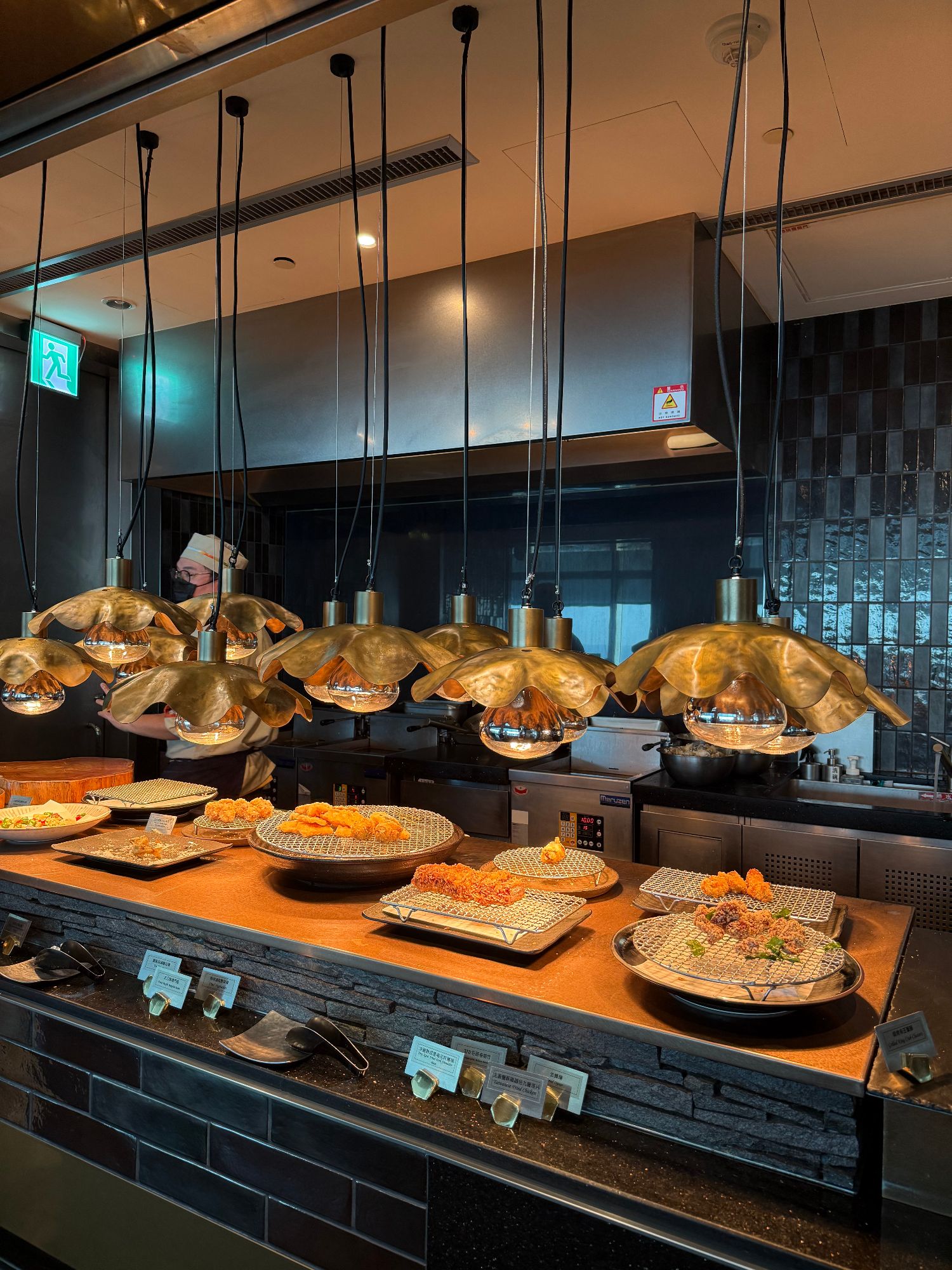 Display of traditional tea service items including glass cups with amber liquid, black teapots, and decorative vessels on wooden surfaces