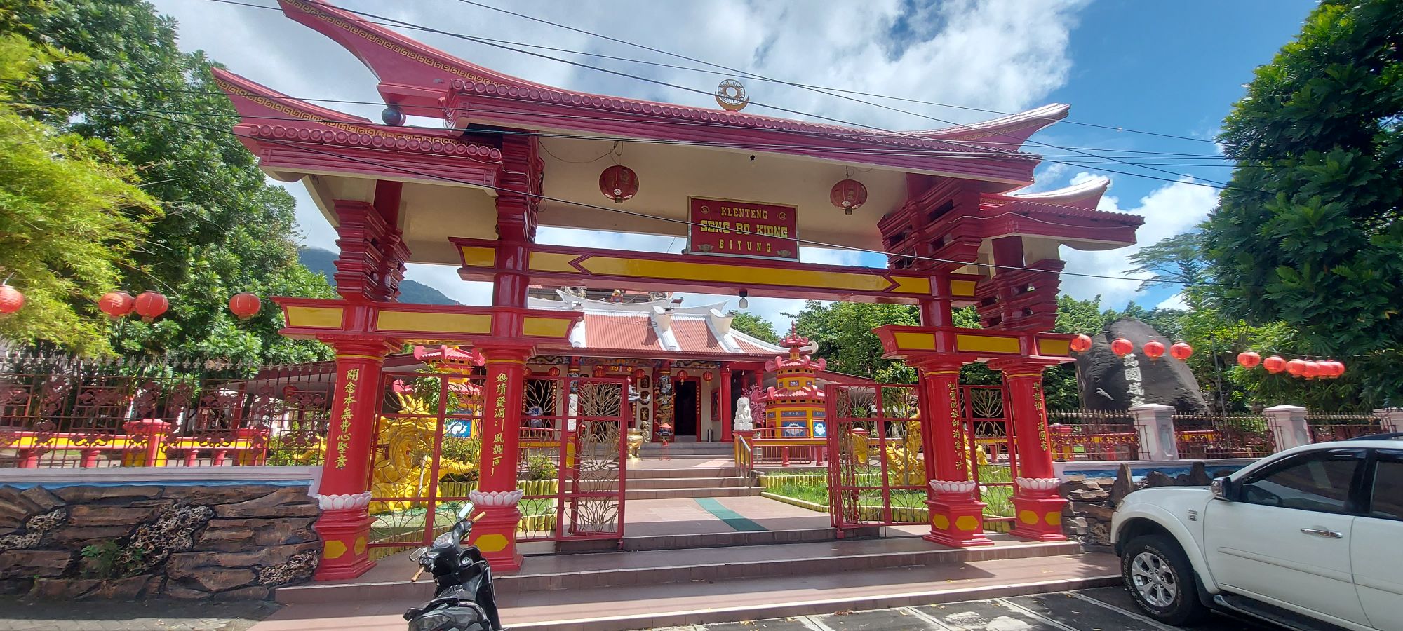 Interior of red and gold Chinese temple with elaborate altar, hanging lanterns, and religious statuary