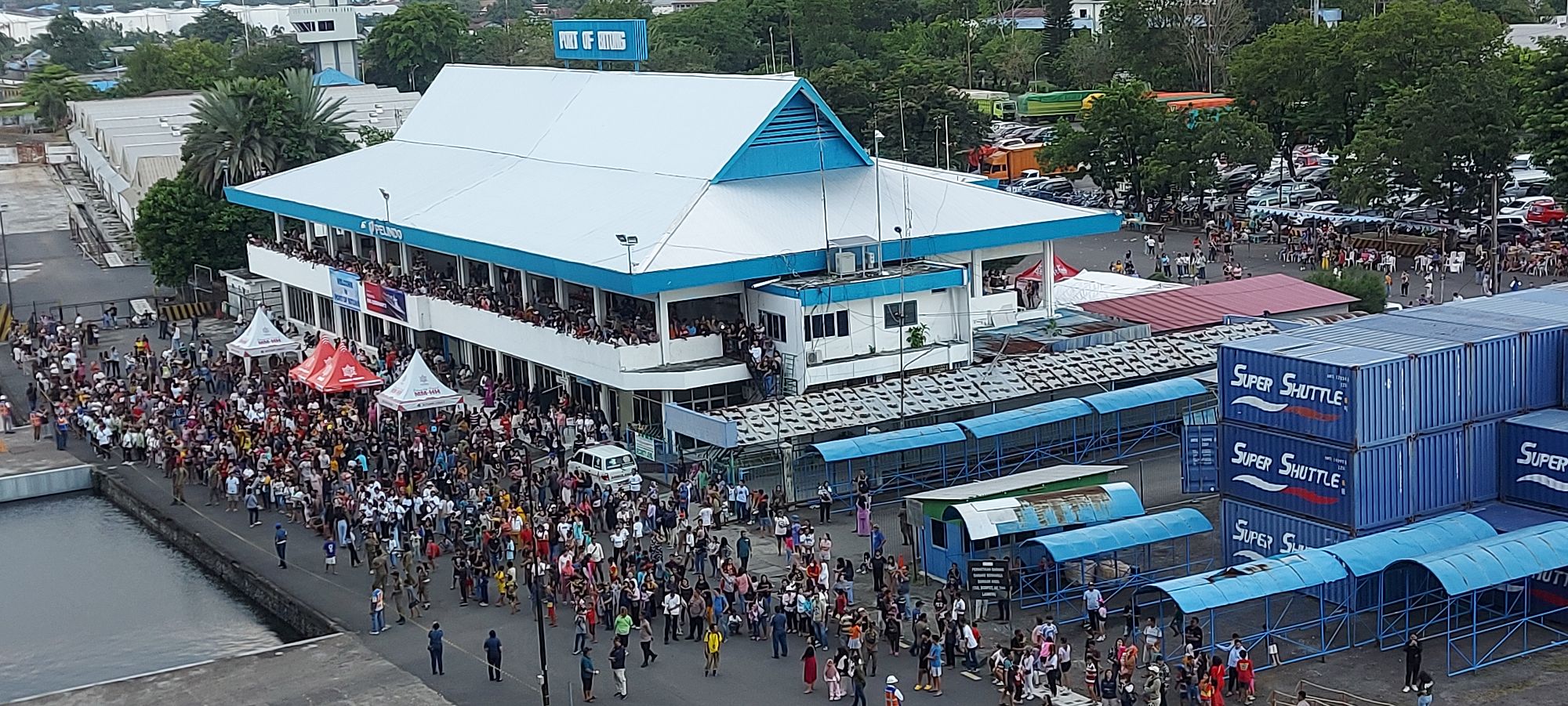 Group of locals and tourists waving at camera during festival gathering at Bitung waterfront