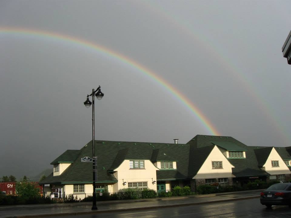 Rainbow arcing over a building with green roof during rainy weather in Canada
