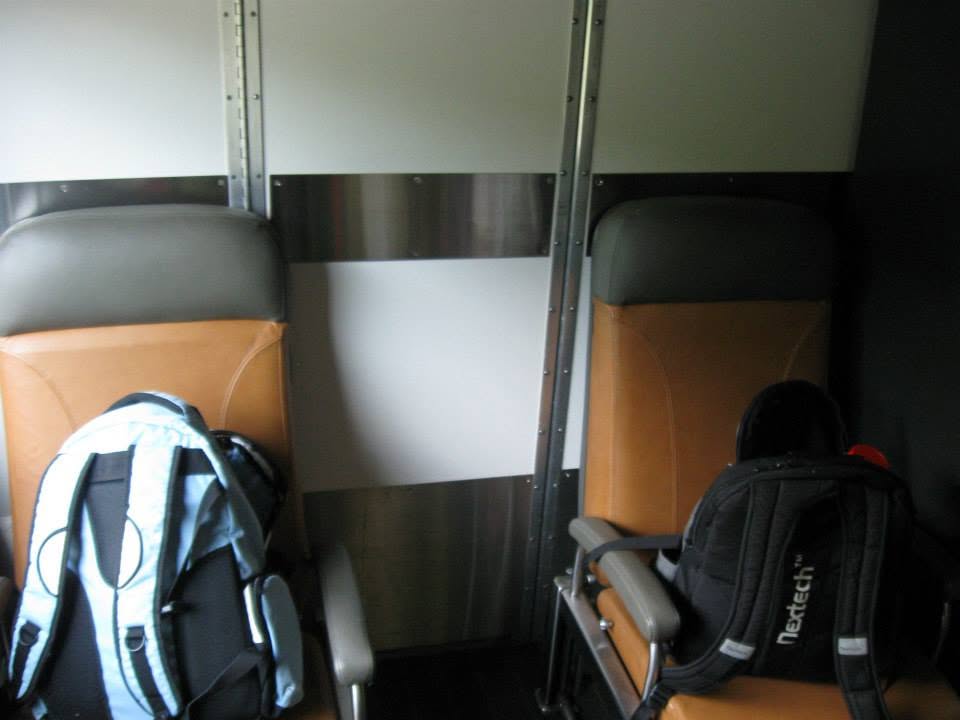 Two backpacks on seats inside a train car with striped upholstery