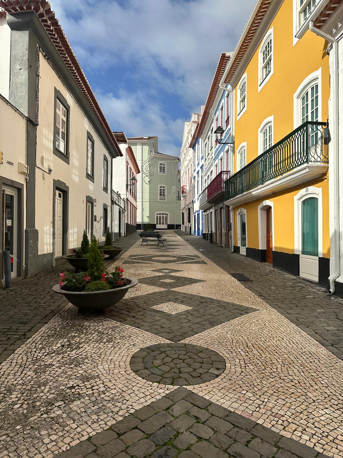 Colorful colonial-style street with yellow, cream, and blue buildings lining a cobblestone plaza