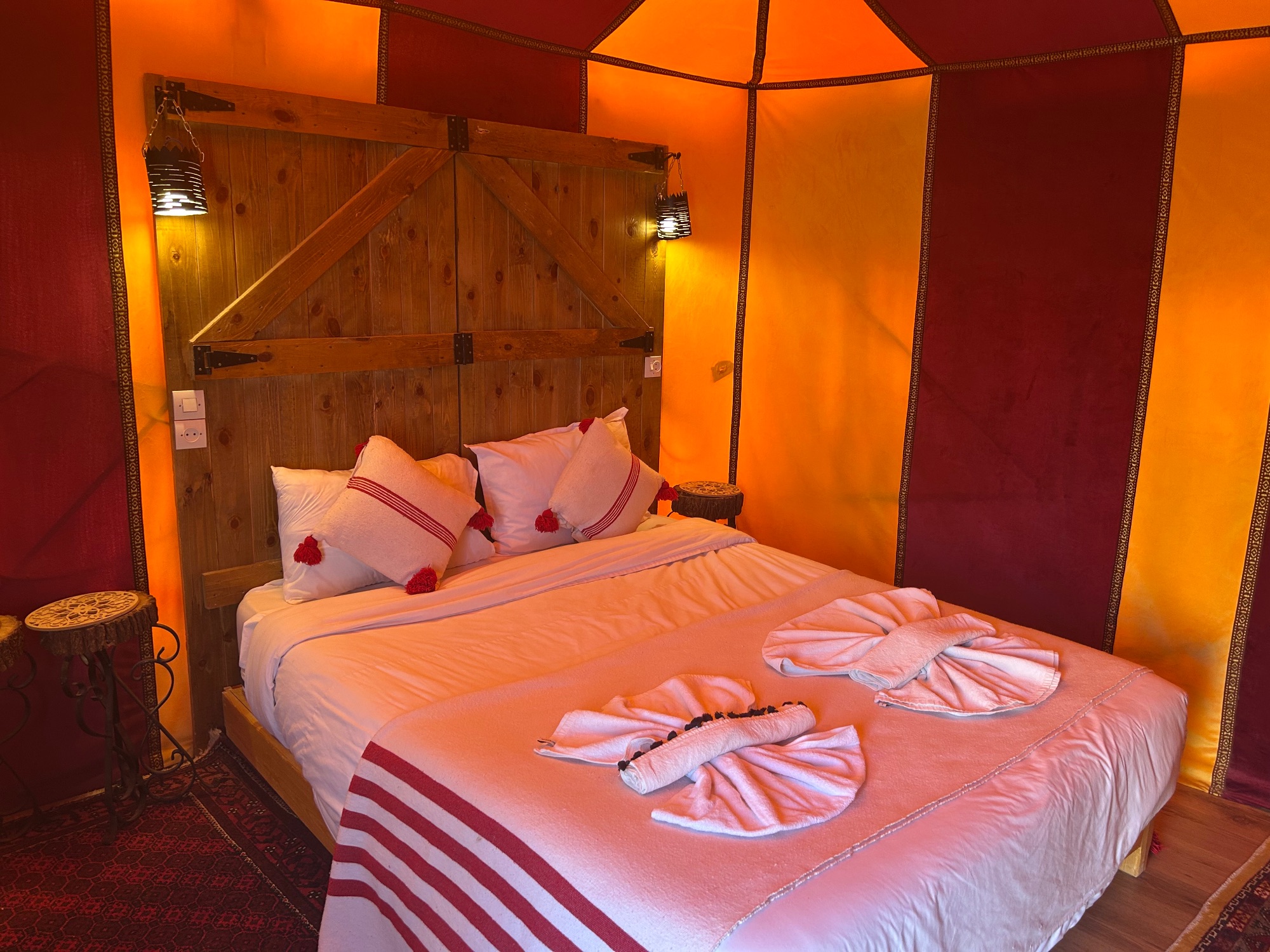 Luxurious bedroom interior with orange and red fabric walls, wooden canopy bed, and decorative pillows