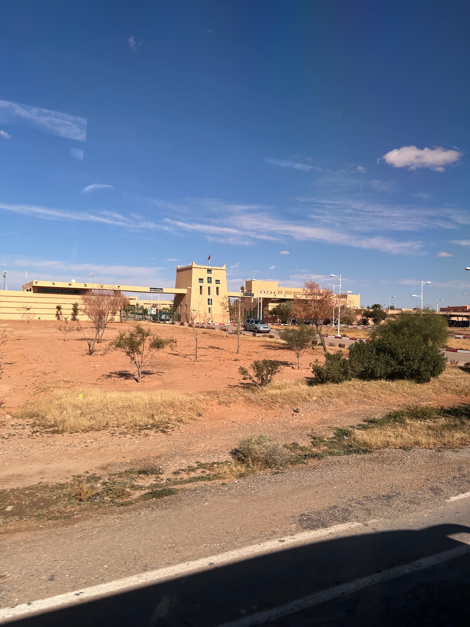 Tan-colored buildings and sparse vegetation in a desert town with clear blue sky