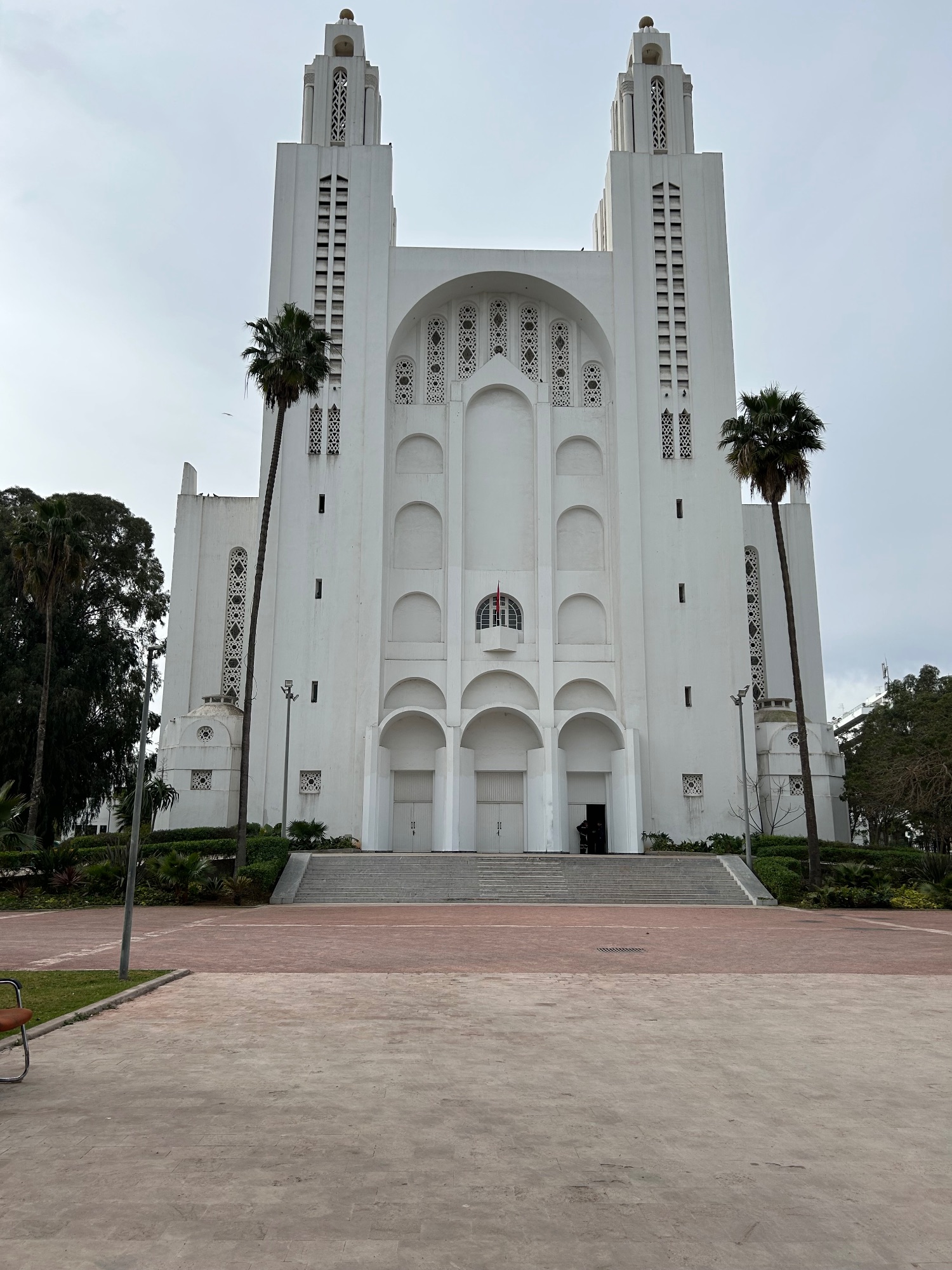 Ornate white mosque with twin minarets and intricate geometric patterns on its facade
