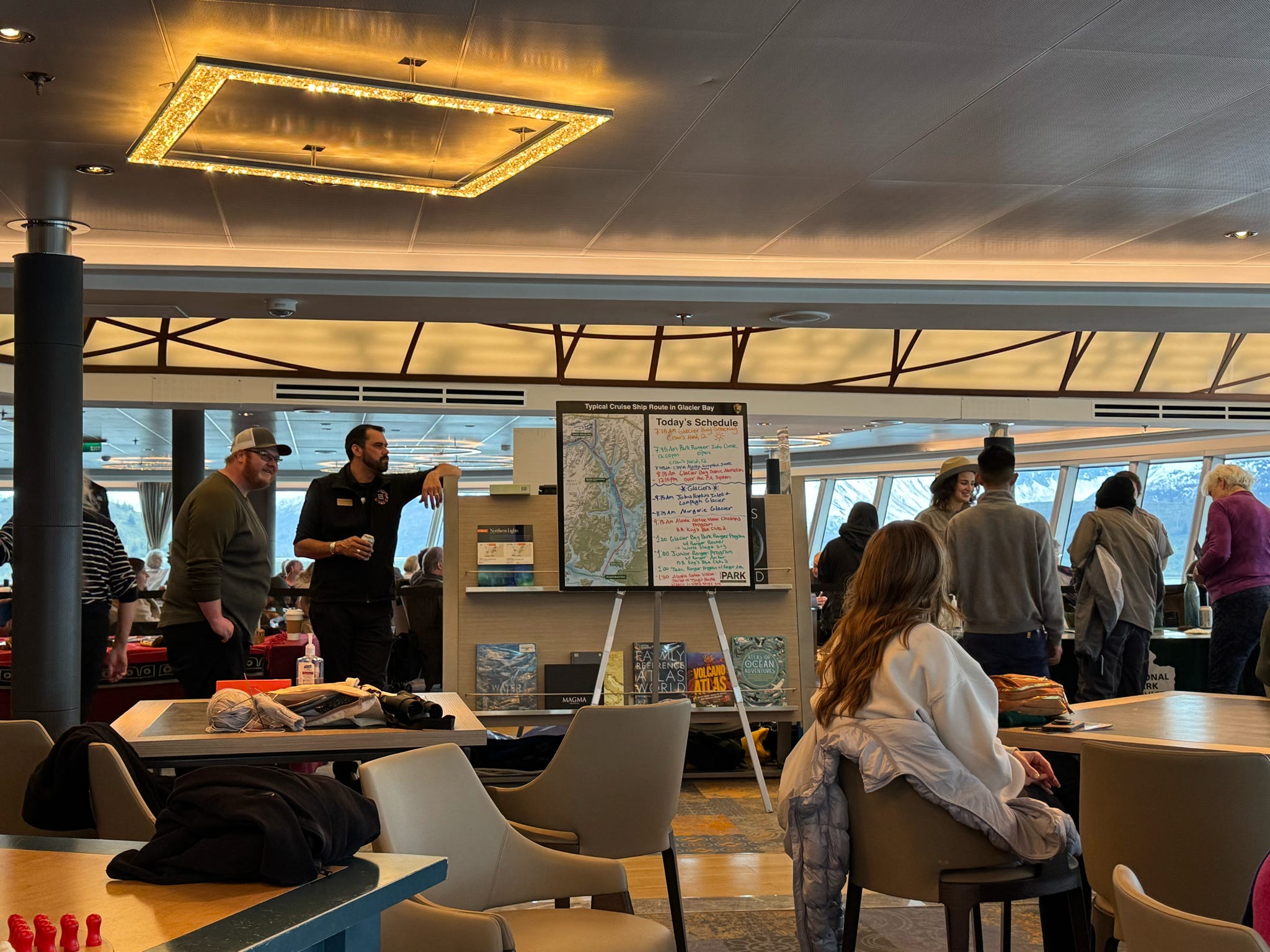 Cruise passengers gather around a Glacier Bay National Park ranger display aboard a ship lounge.