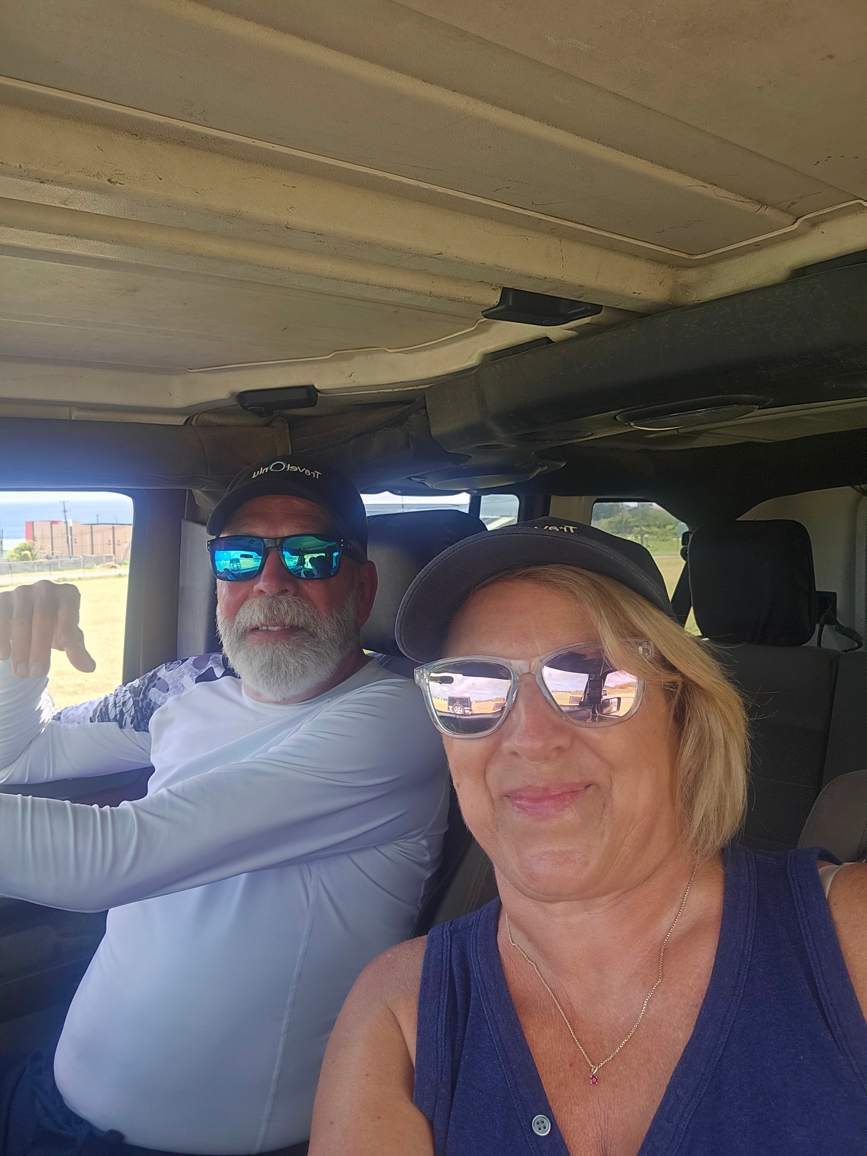 Two travelers in vehicle with volcanic mountain landscape visible through windshield