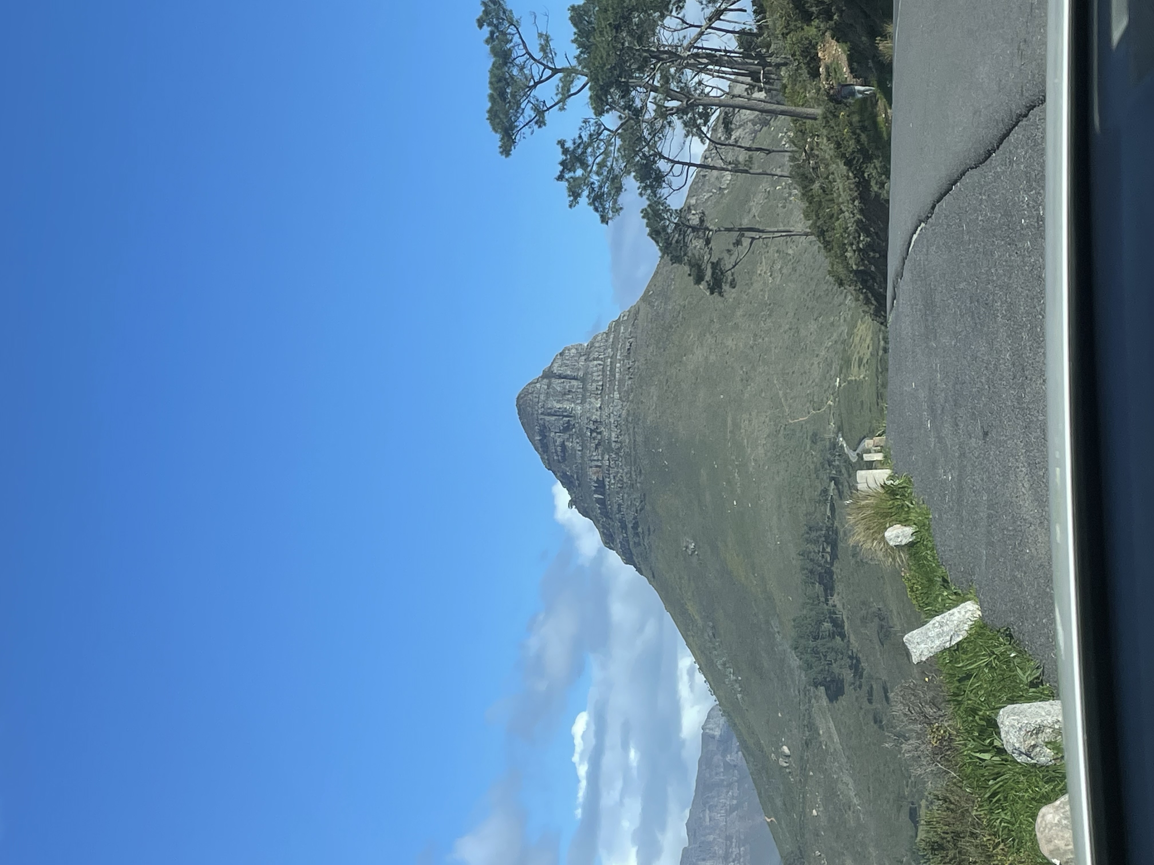 View from car windshield of a distinctive cone-shaped mountain on a winding road in Cape Town