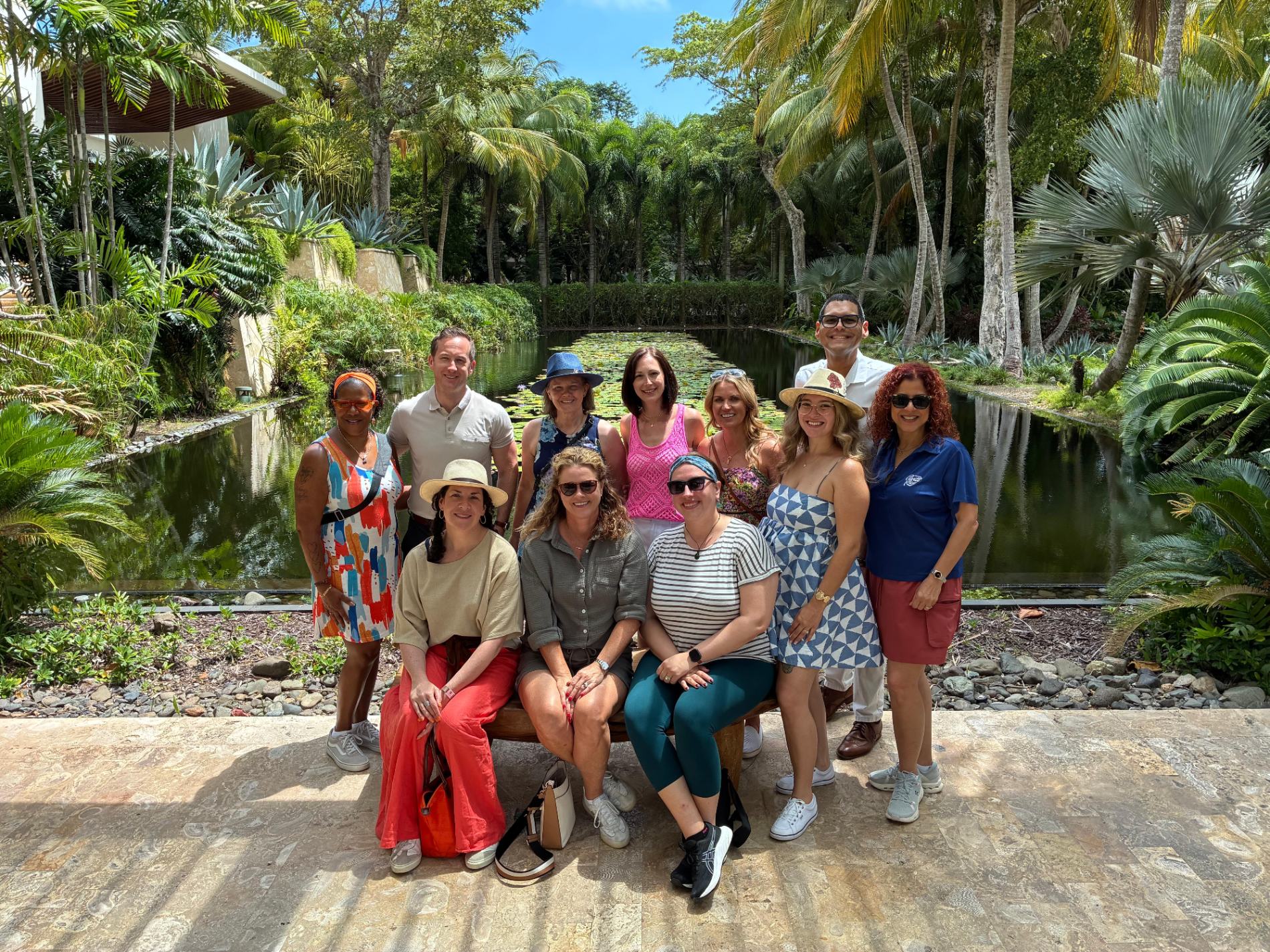 Visitors posing by a tranquil river surrounded by dense tropical vegetation and palm trees